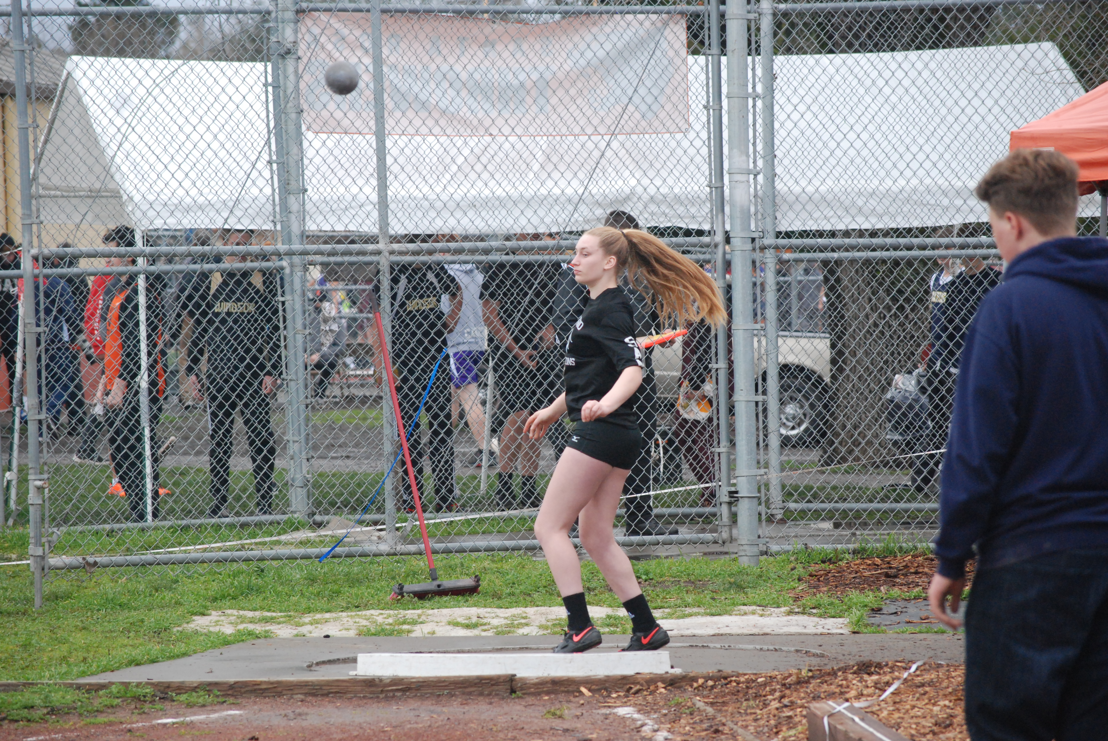 Athlete prepares for pole vault on a track with others watching.