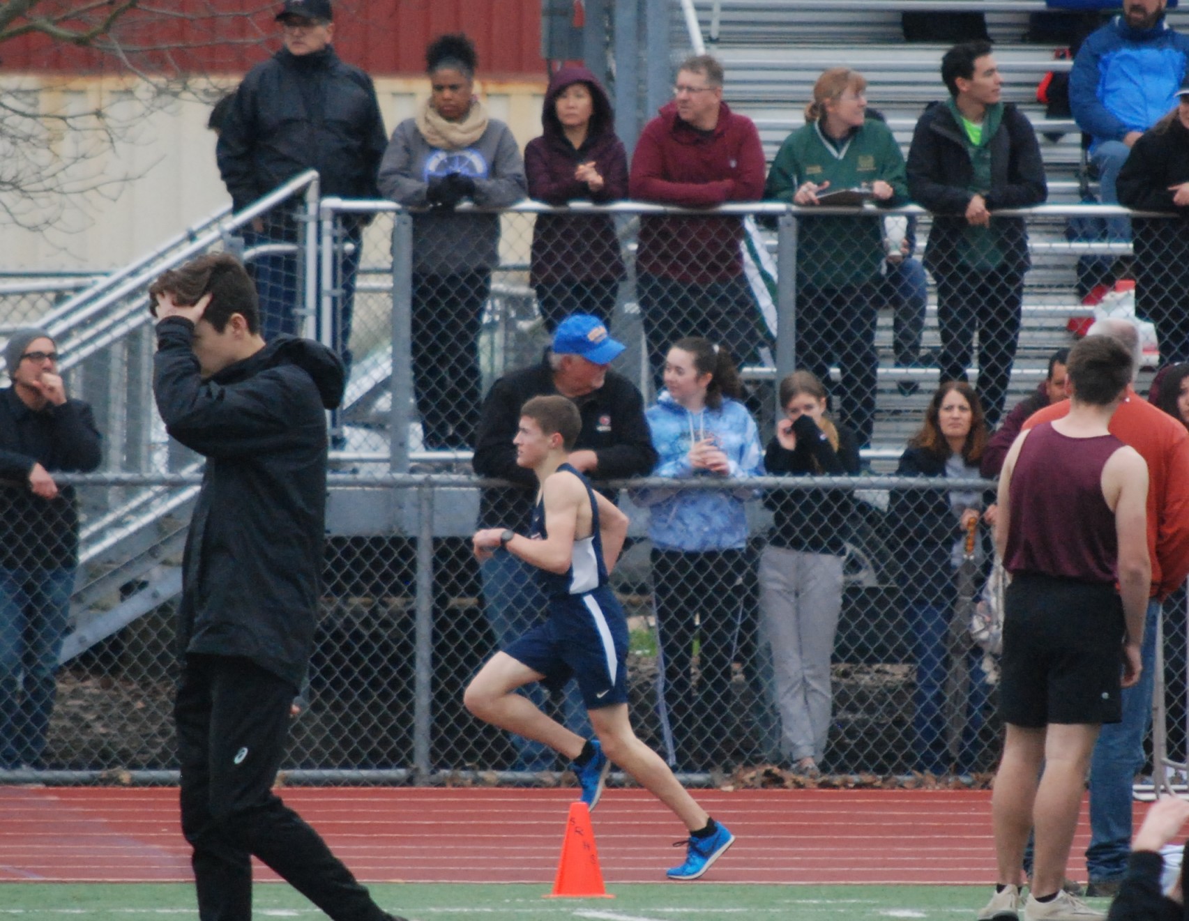 Athlete prepares for pole vault on a track with others watching.