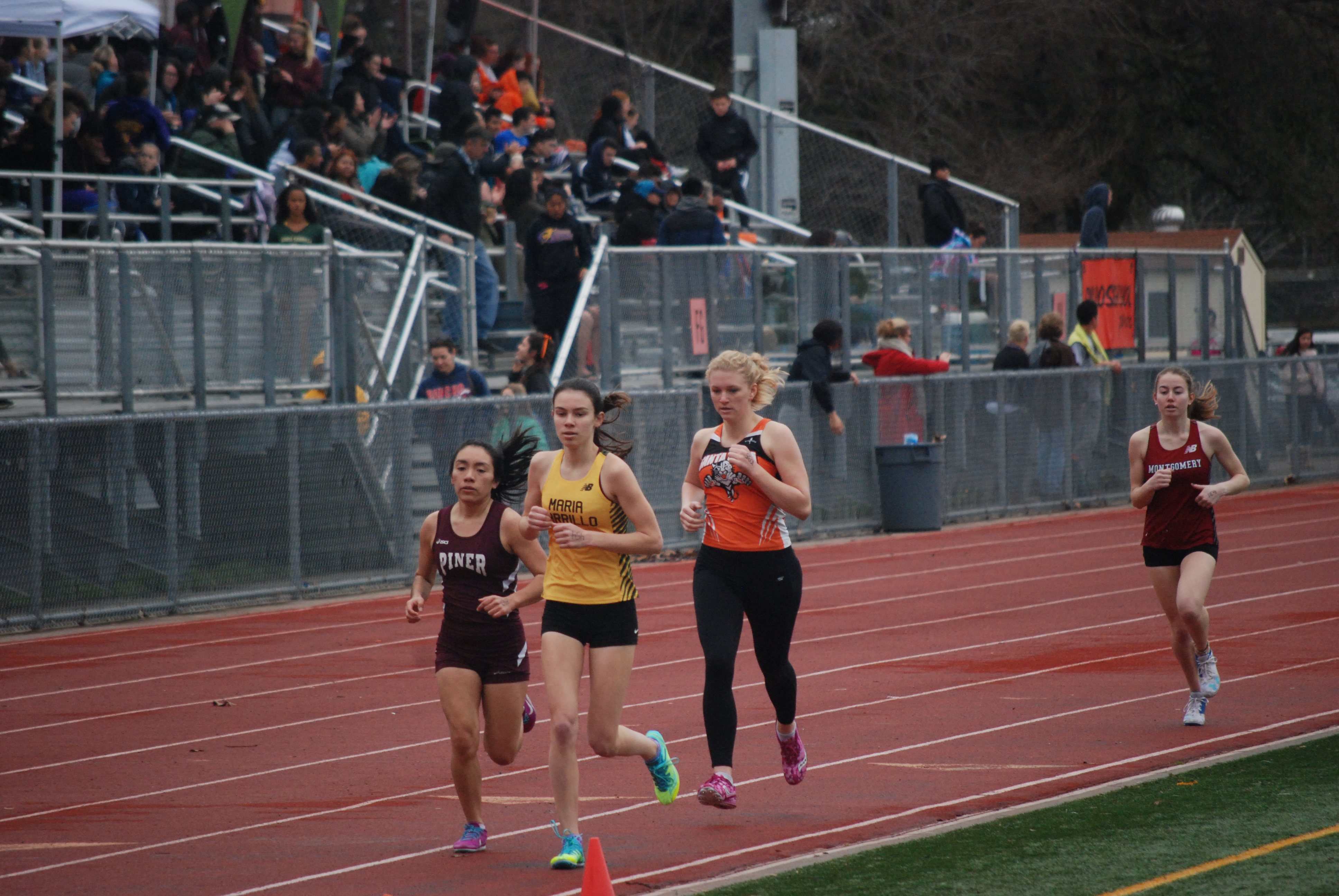 Athlete prepares for pole vault on a track with others watching.