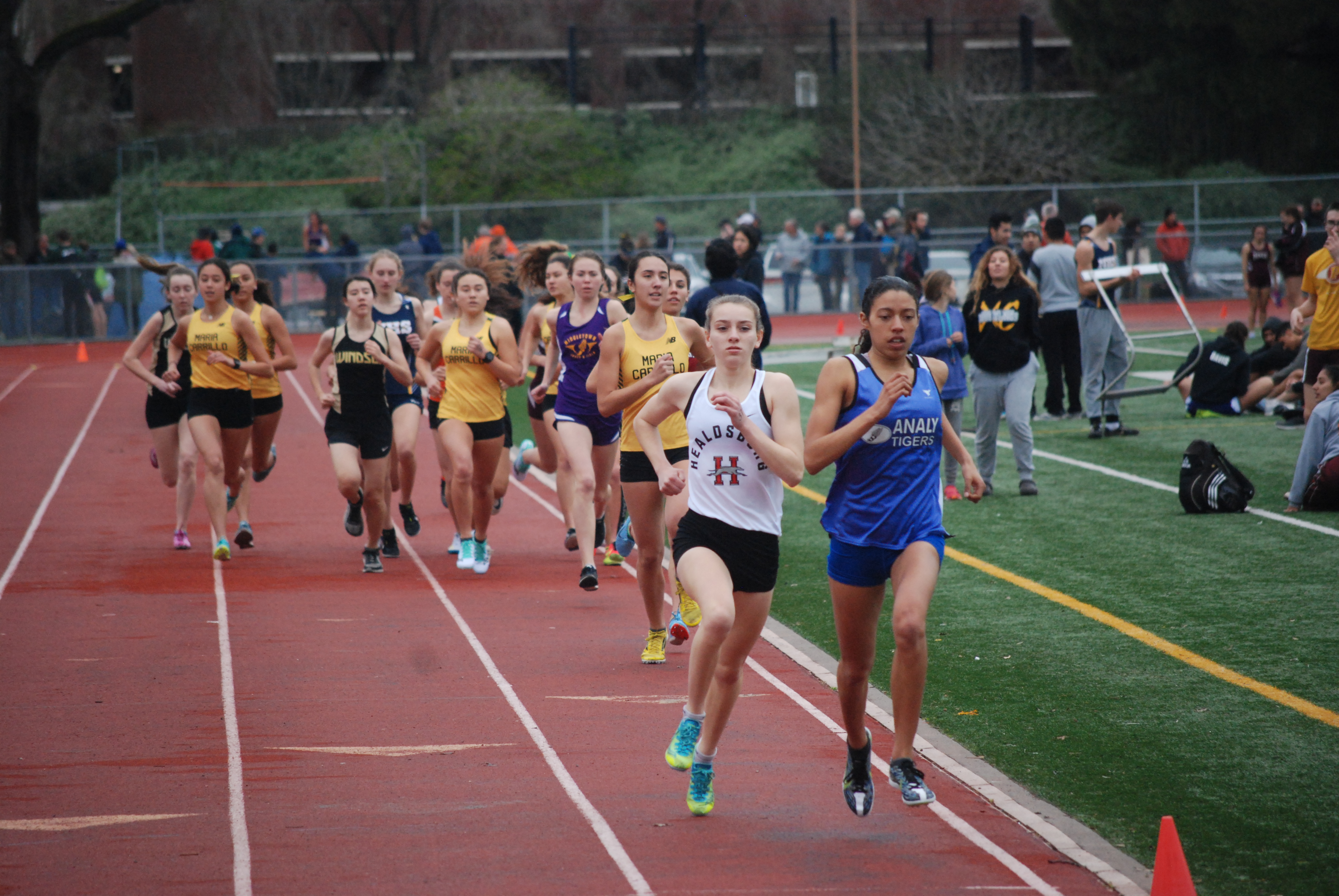 Athlete prepares for pole vault on a track with others watching.