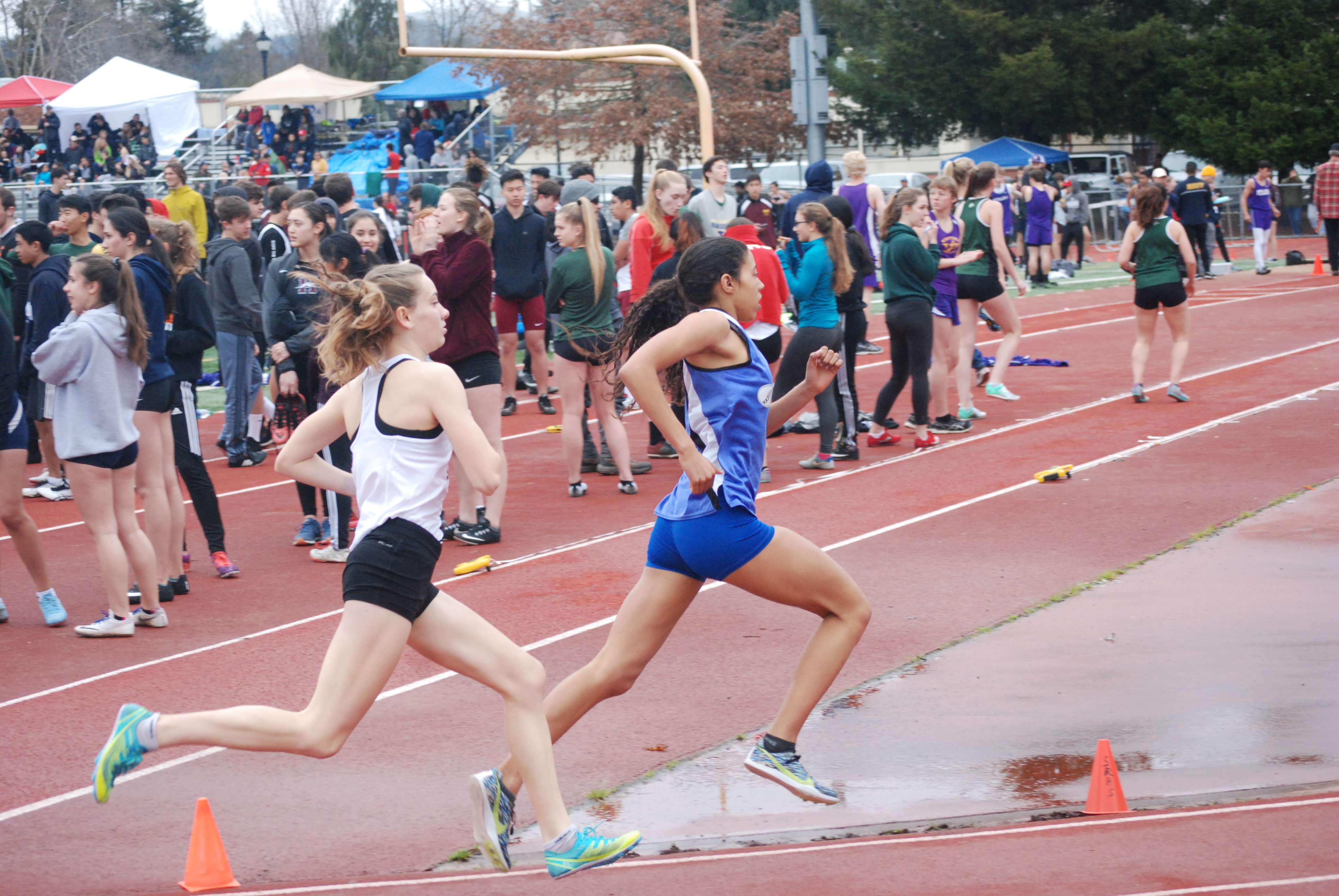 Athlete prepares for pole vault on a track with others watching.