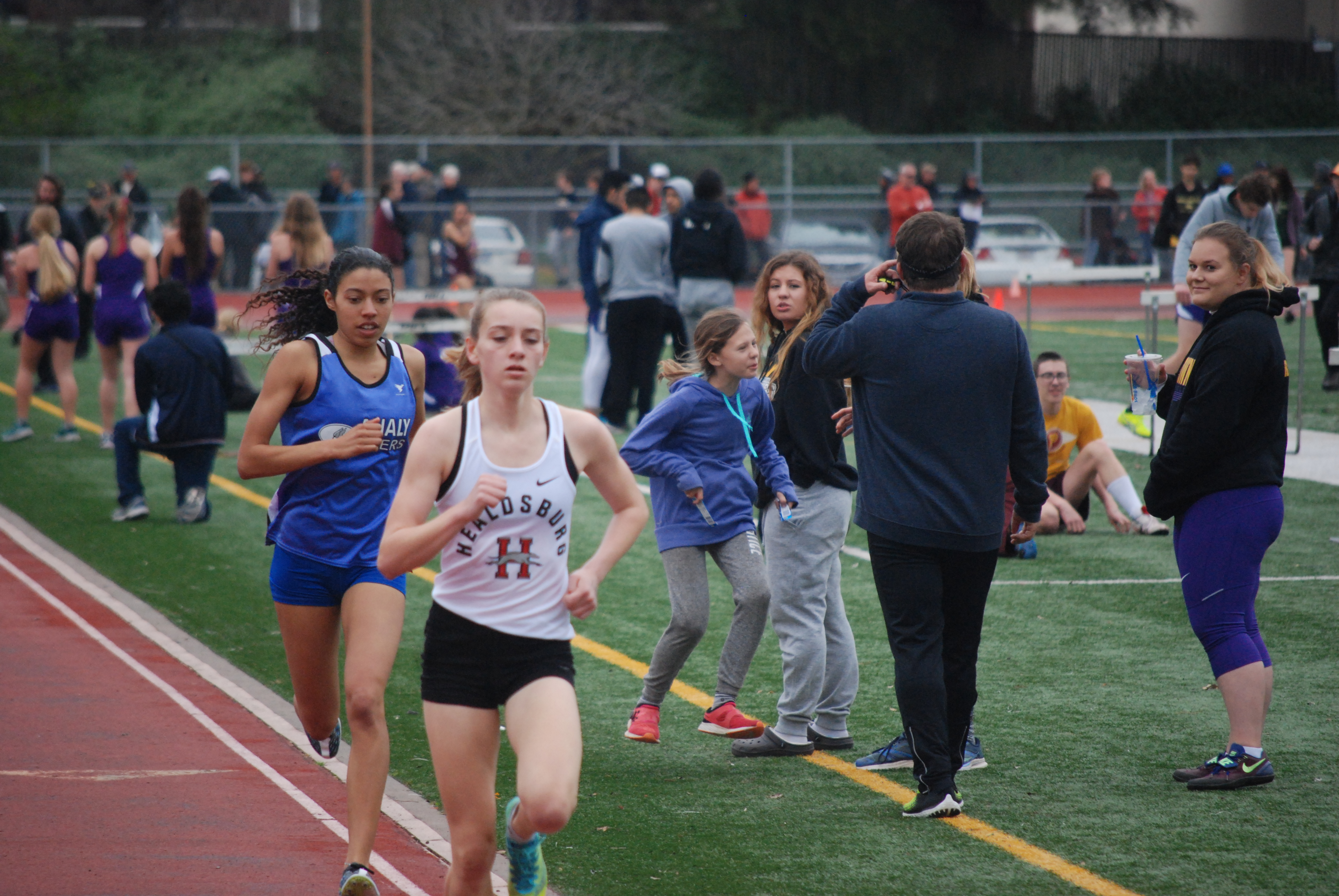 Athlete prepares for pole vault on a track with others watching.
