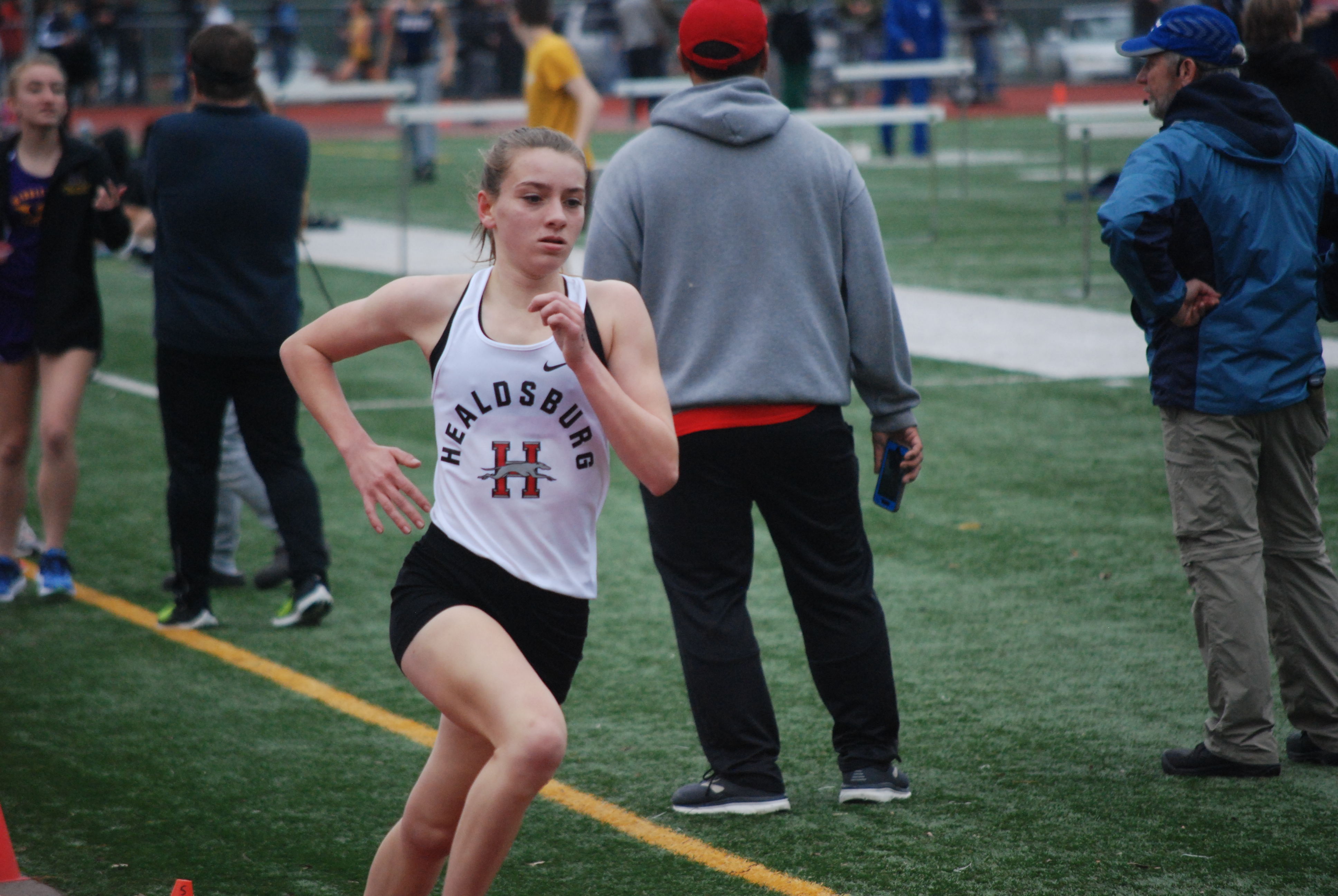 Athlete prepares for pole vault on a track with others watching.