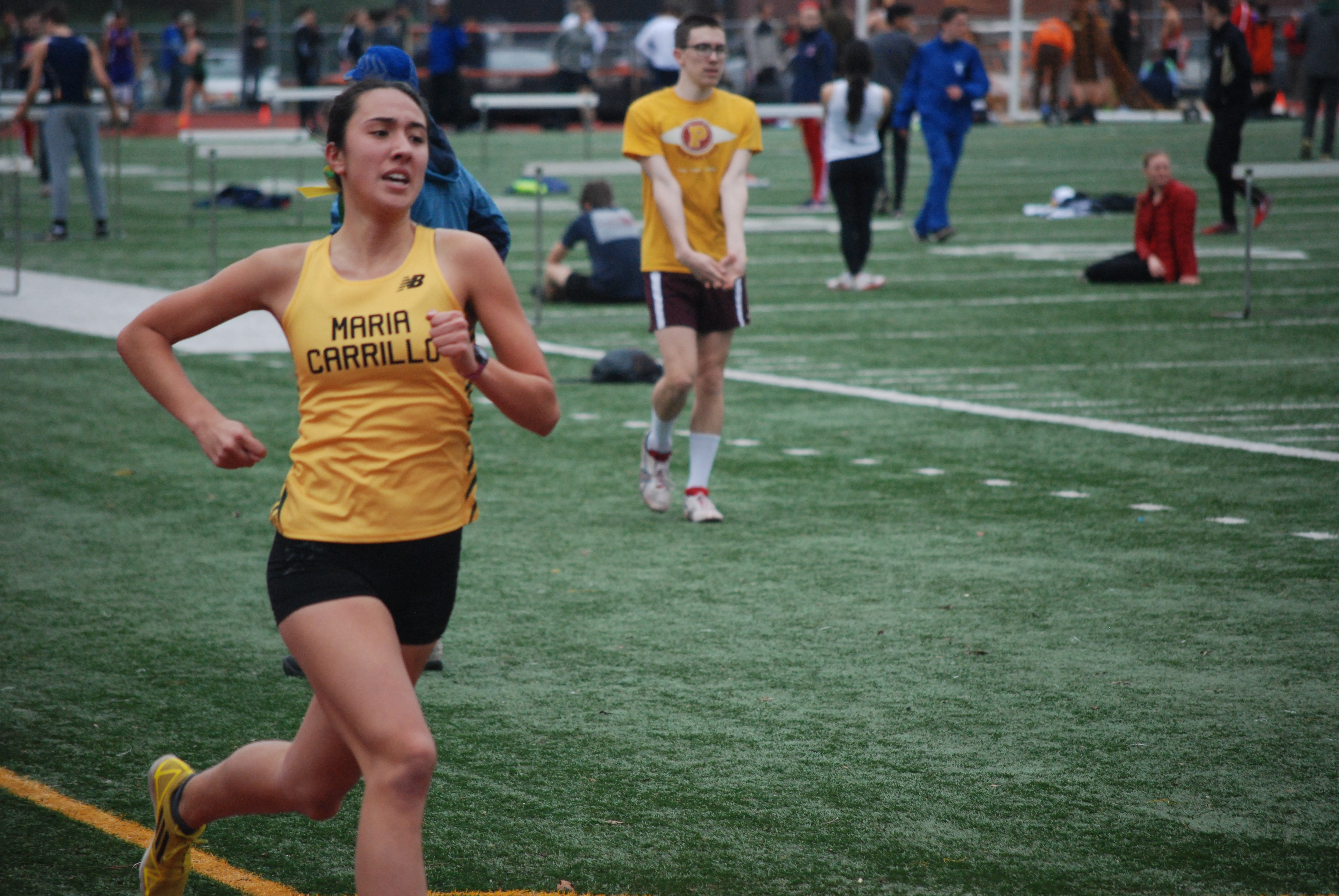 Athlete prepares for pole vault on a track with others watching.