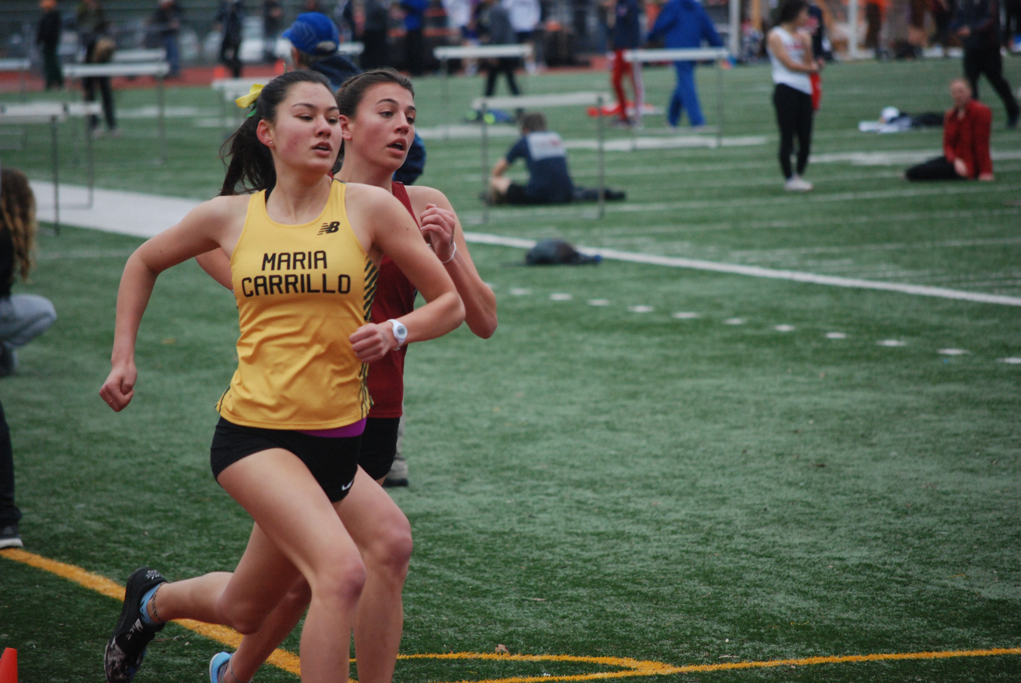Athlete prepares for pole vault on a track with others watching.