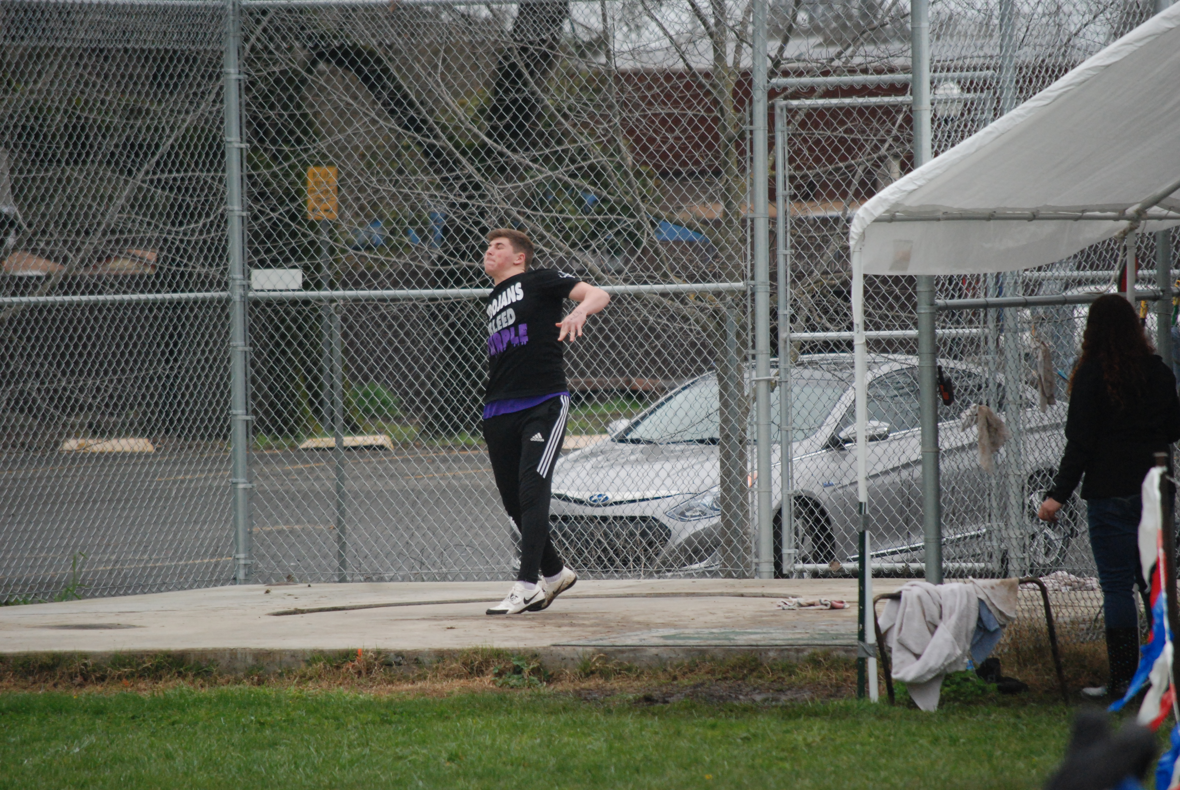 Athlete prepares for pole vault on a track with others watching.