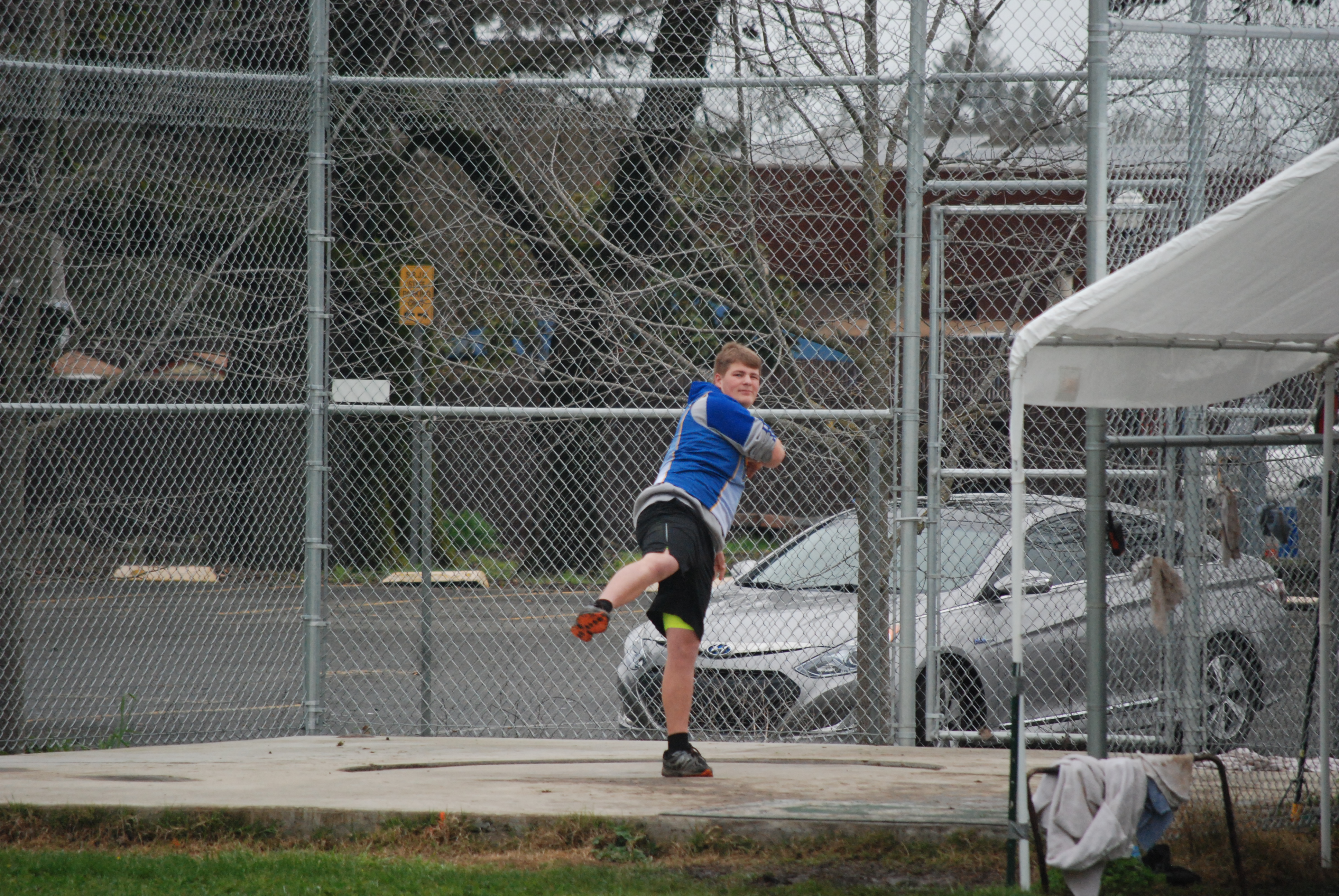Athlete prepares for pole vault on a track with others watching.