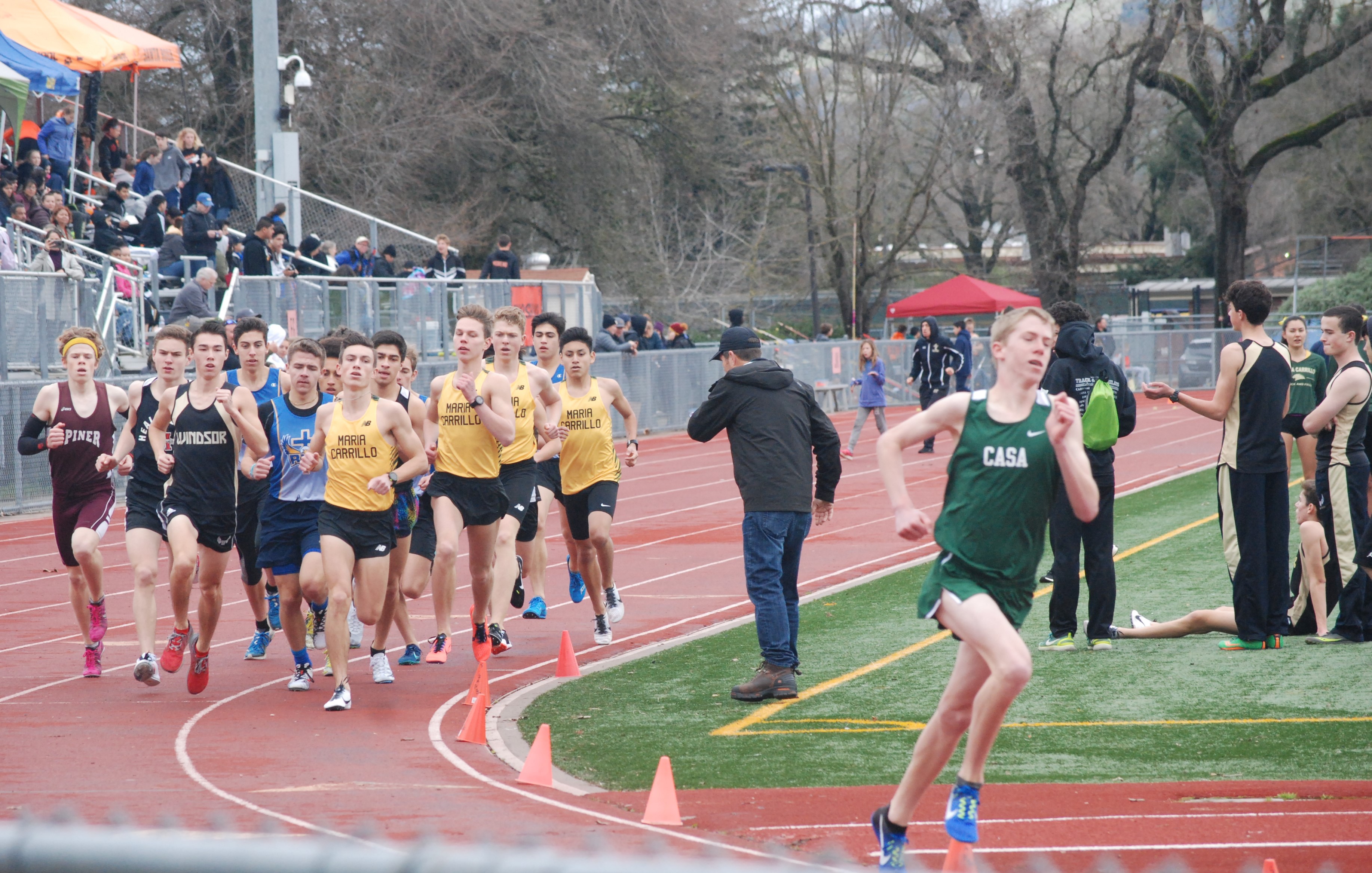 Athlete prepares for pole vault on a track with others watching.