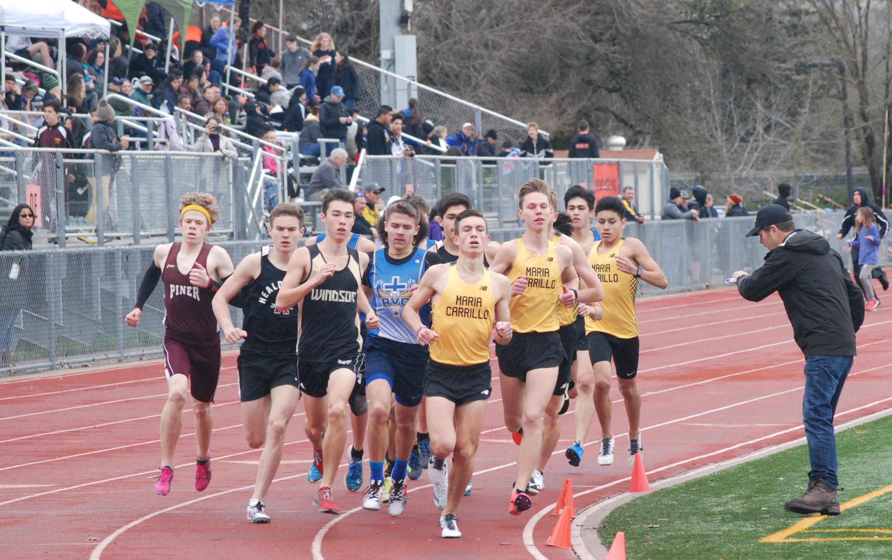Athlete prepares for pole vault on a track with others watching.