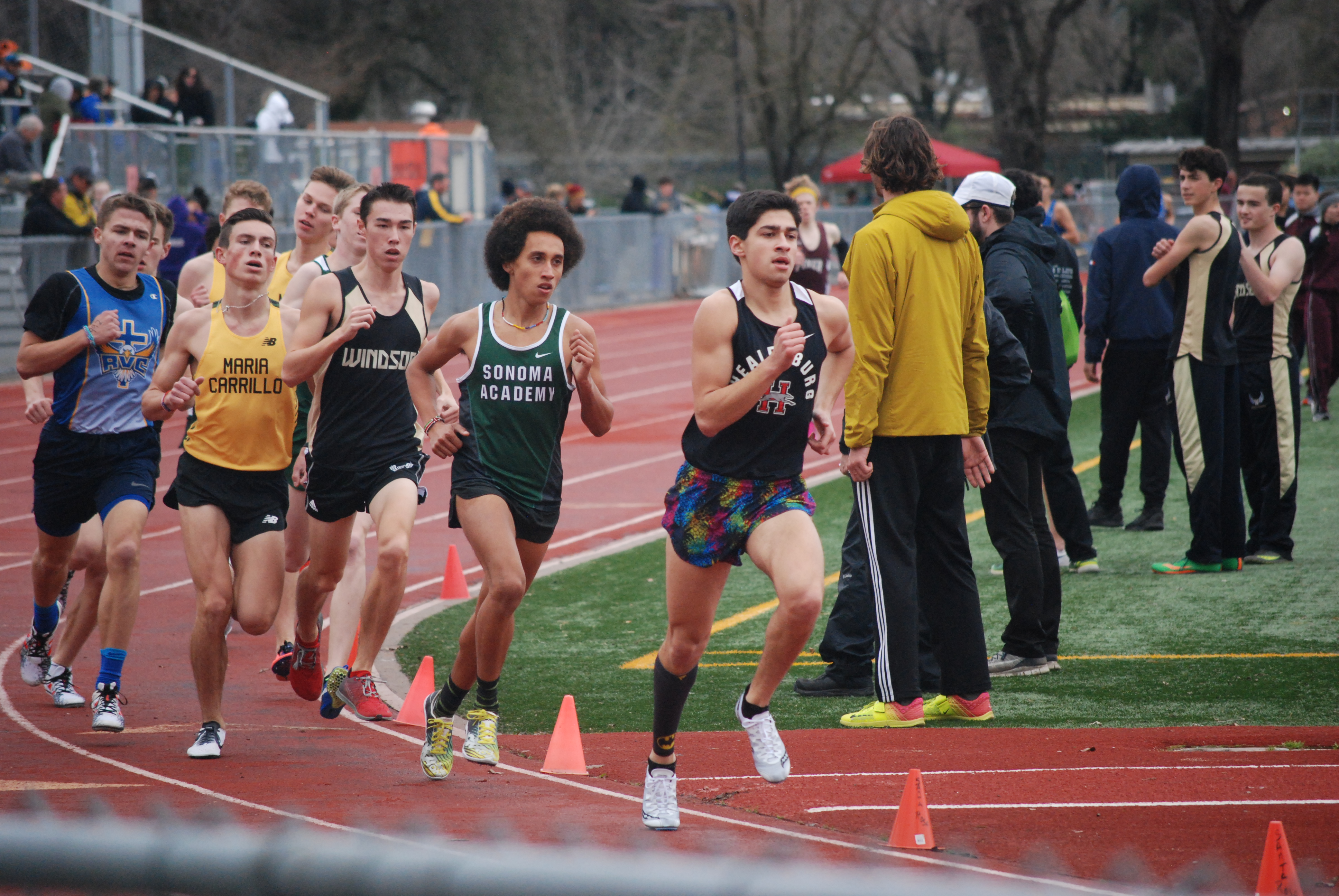 Athlete prepares for pole vault on a track with others watching.