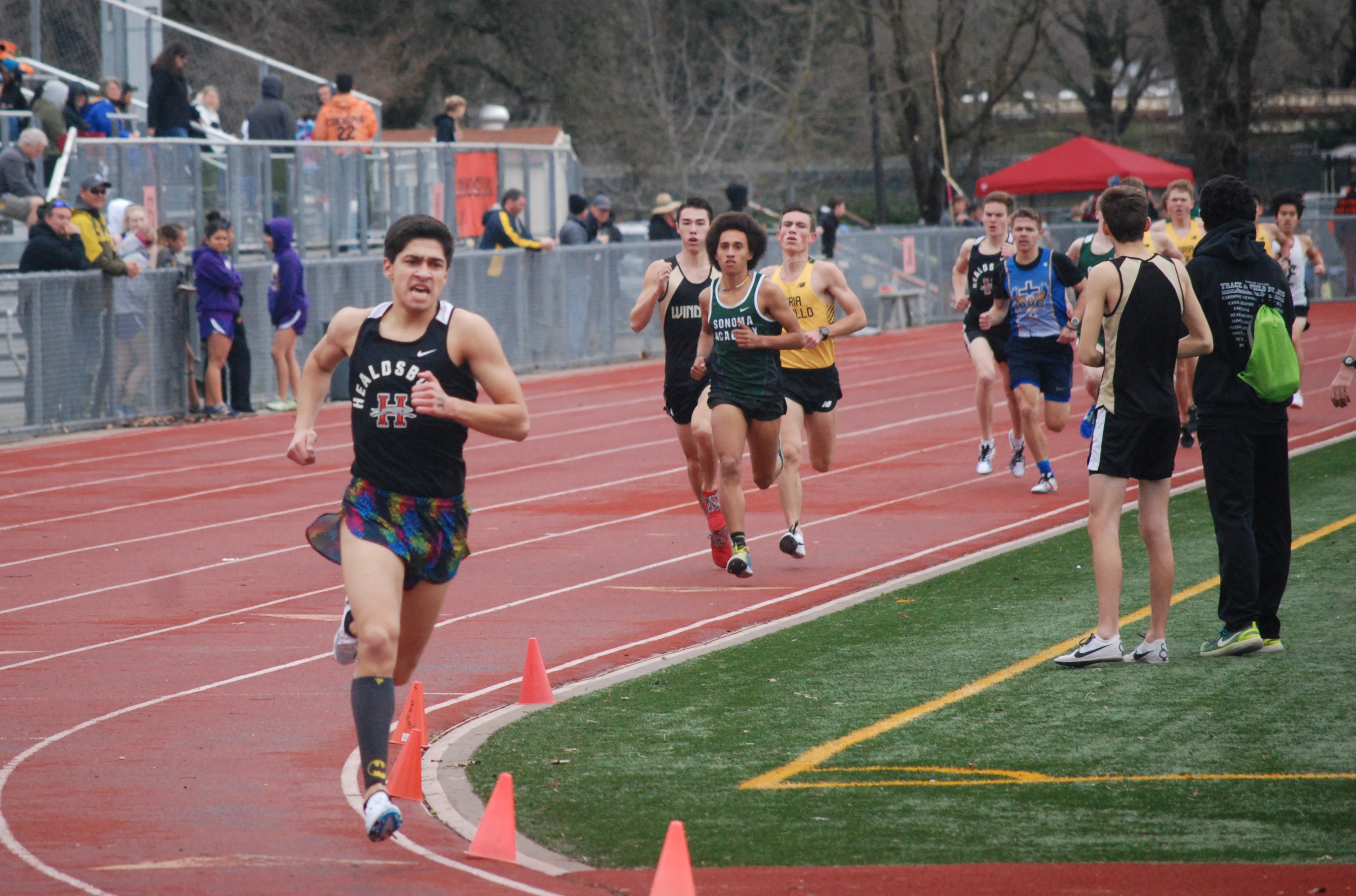 Athlete prepares for pole vault on a track with others watching.