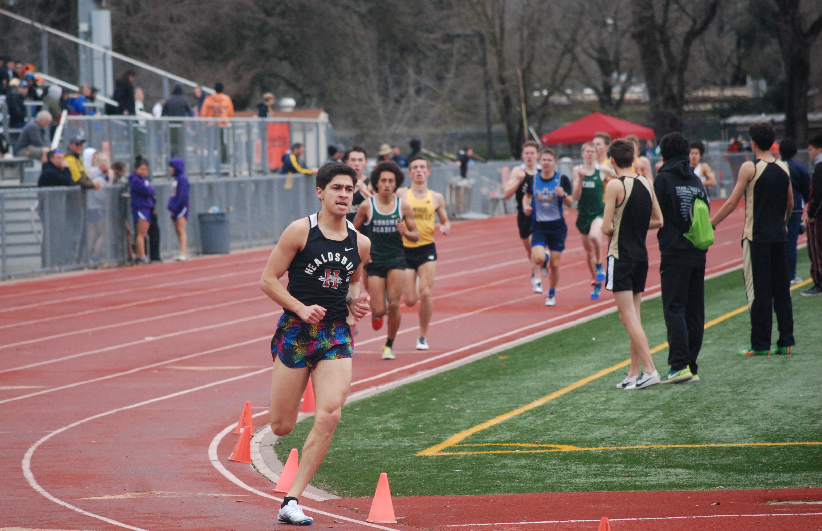 Athlete prepares for pole vault on a track with others watching.
