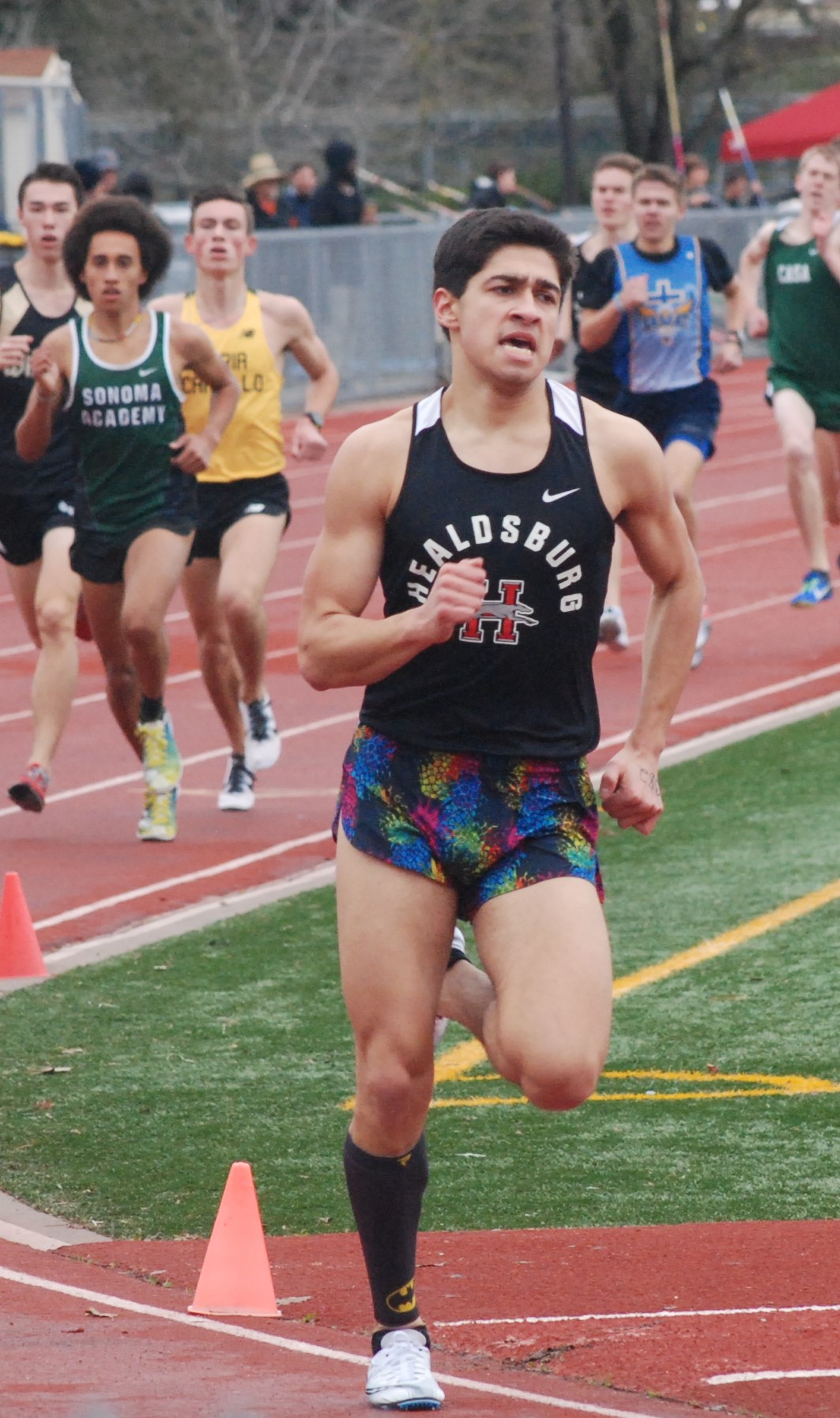 Athlete prepares for pole vault on a track with others watching.