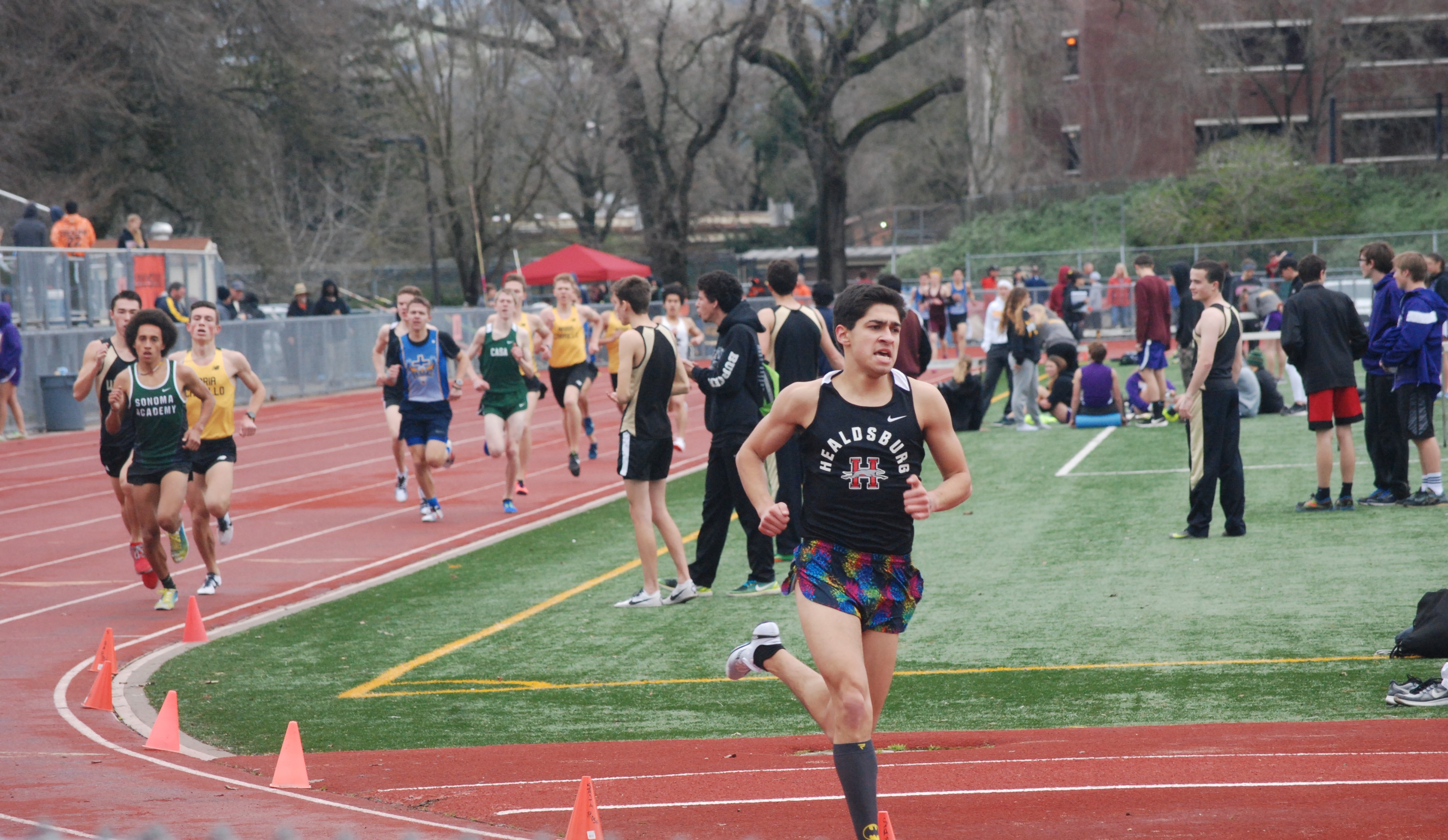 Athlete prepares for pole vault on a track with others watching.