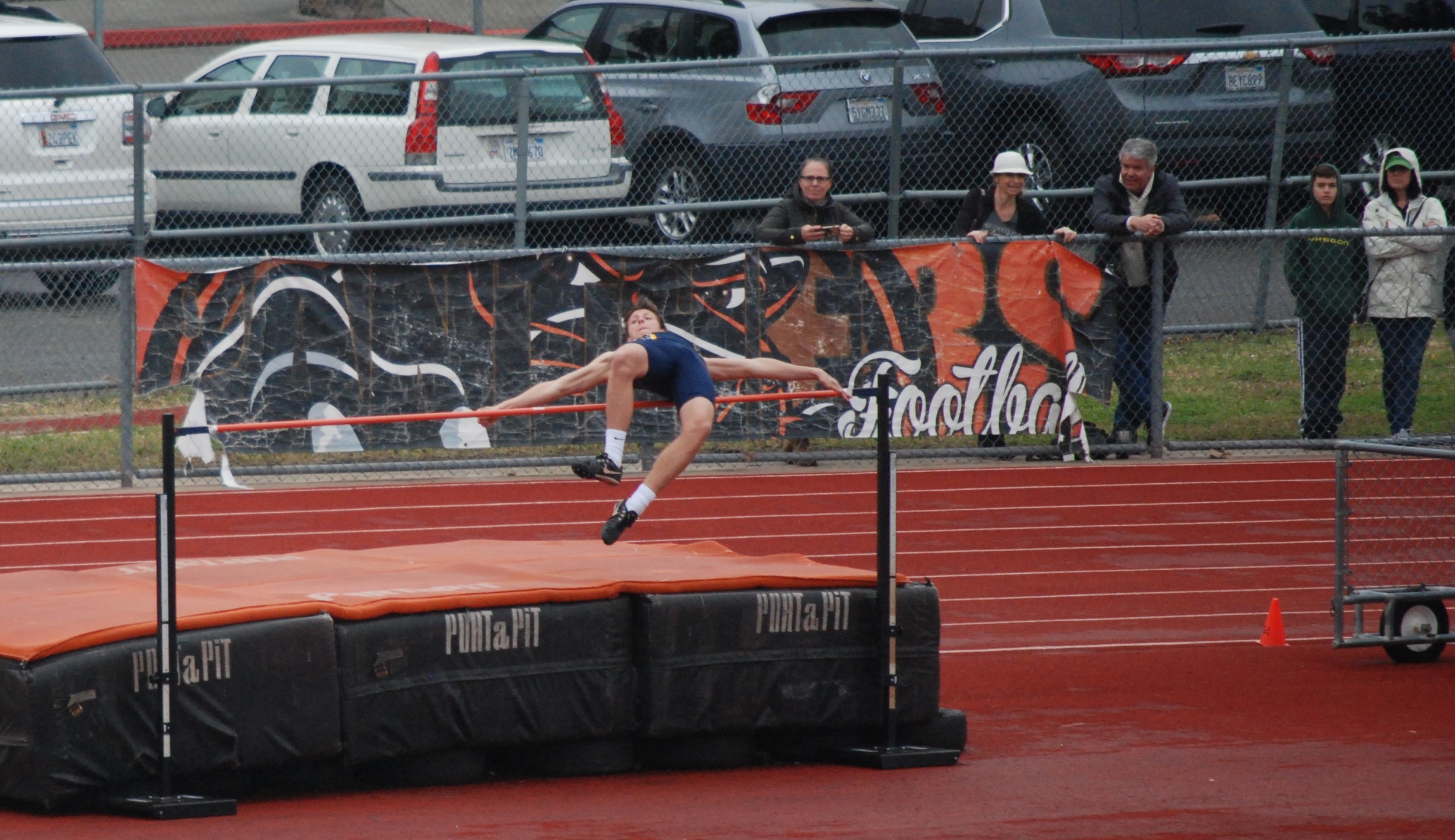 Athlete prepares for pole vault on a track with others watching.
