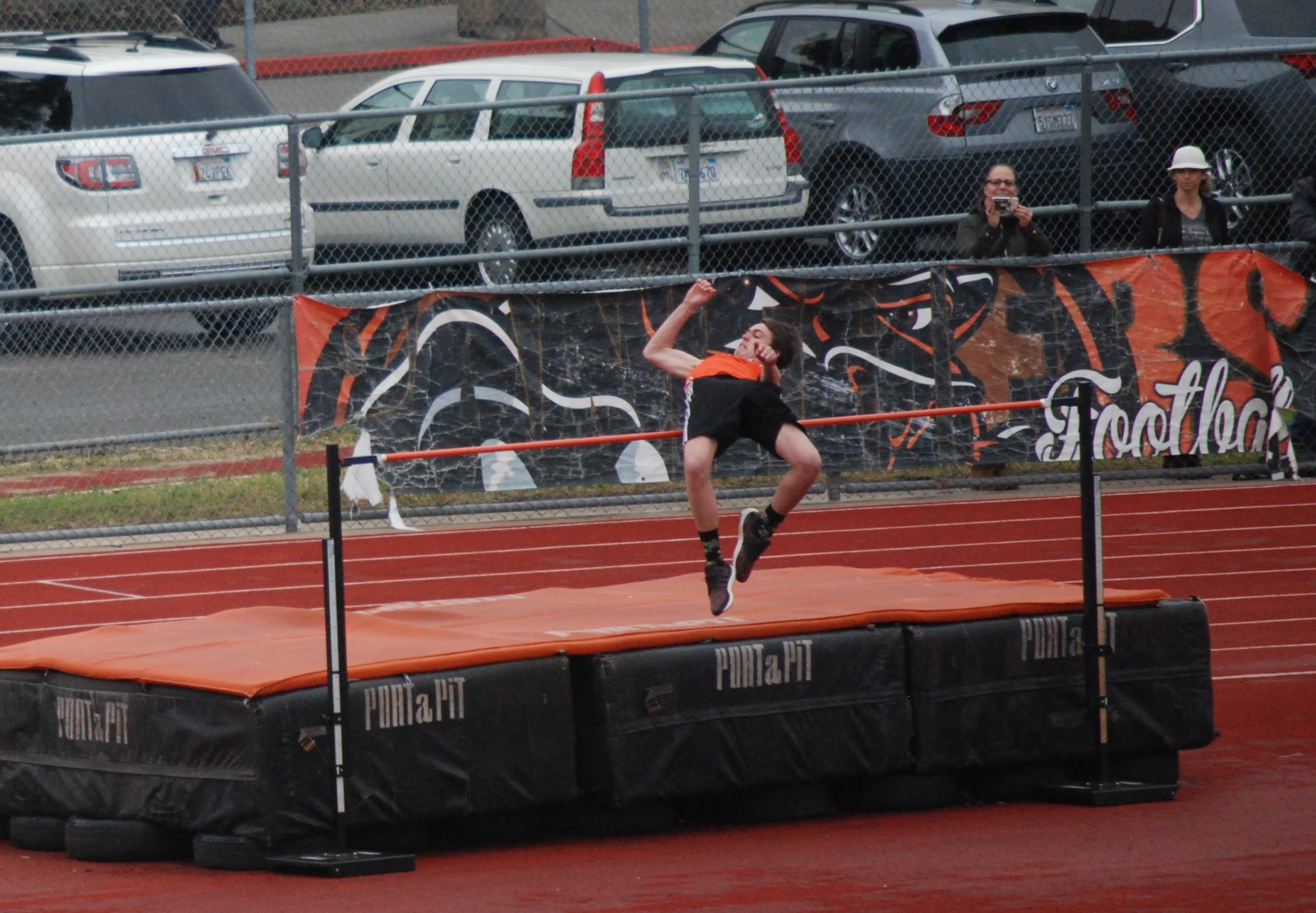 Athlete prepares for pole vault on a track with others watching.