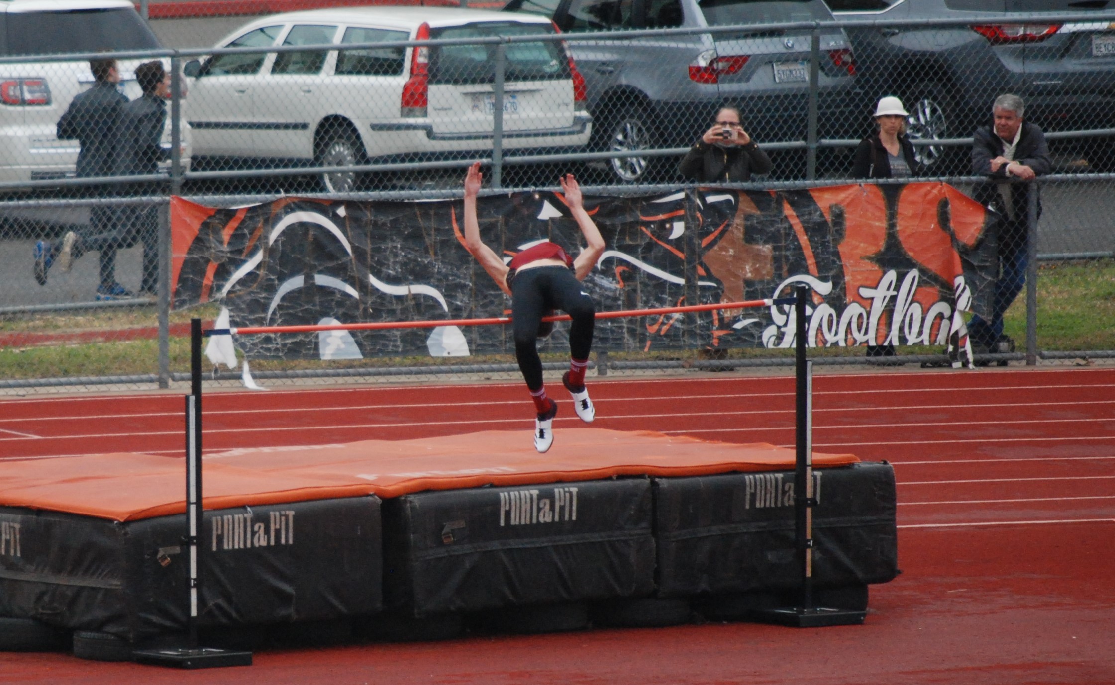 Athlete prepares for pole vault on a track with others watching.