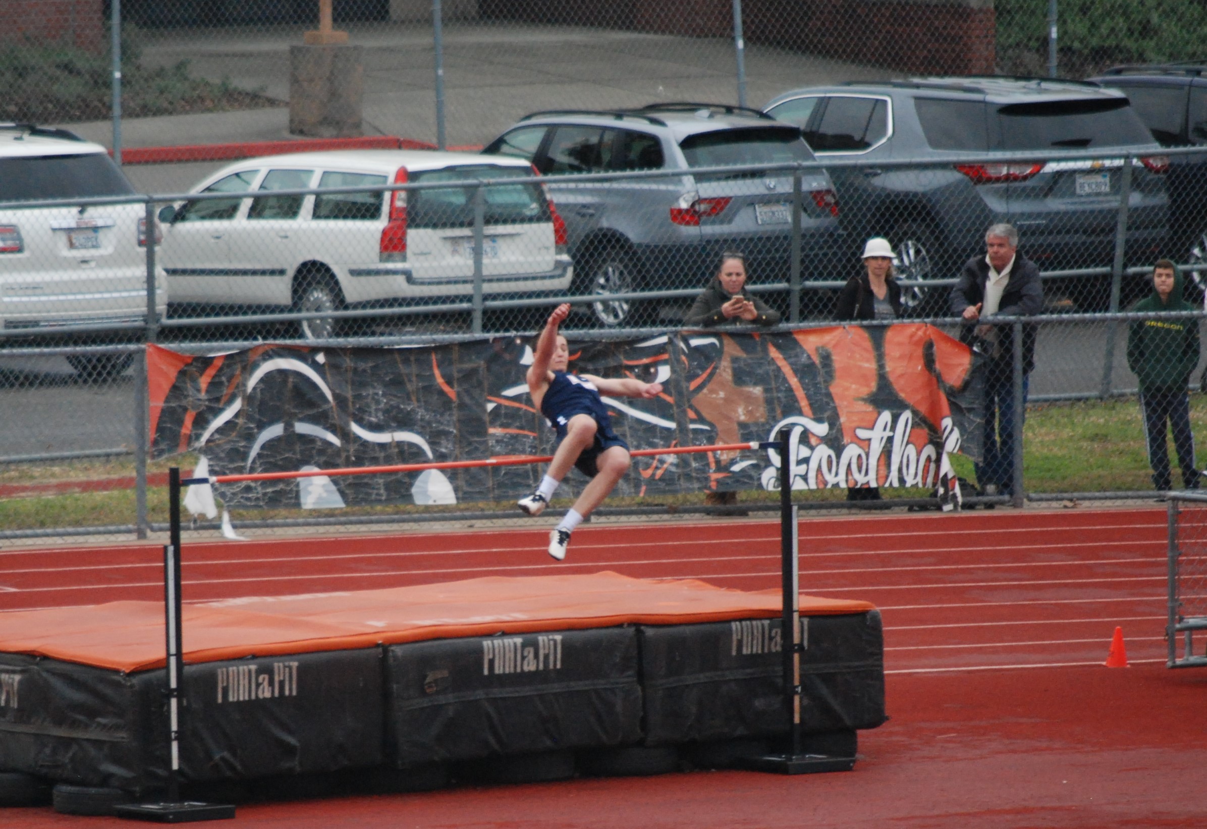 Athlete prepares for pole vault on a track with others watching.