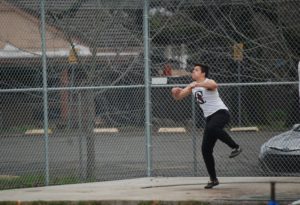 Athlete prepares for pole vault on a track with others watching.