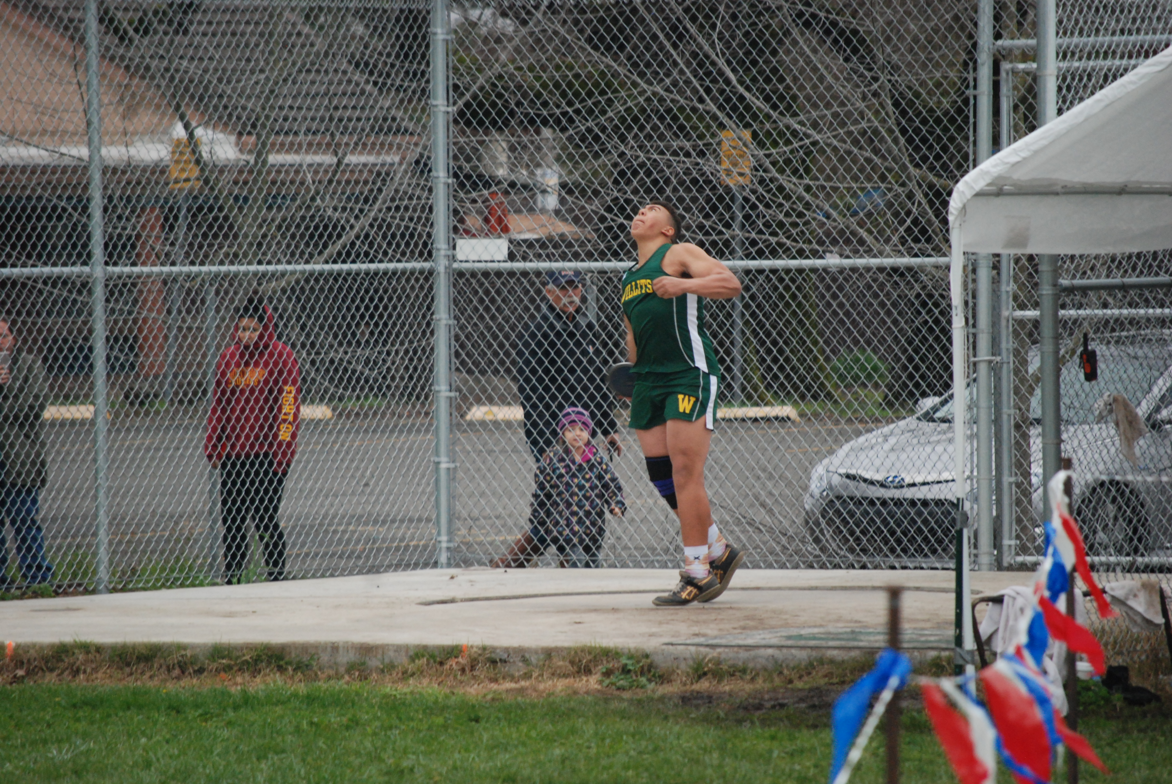 Athlete prepares for pole vault on a track with others watching.