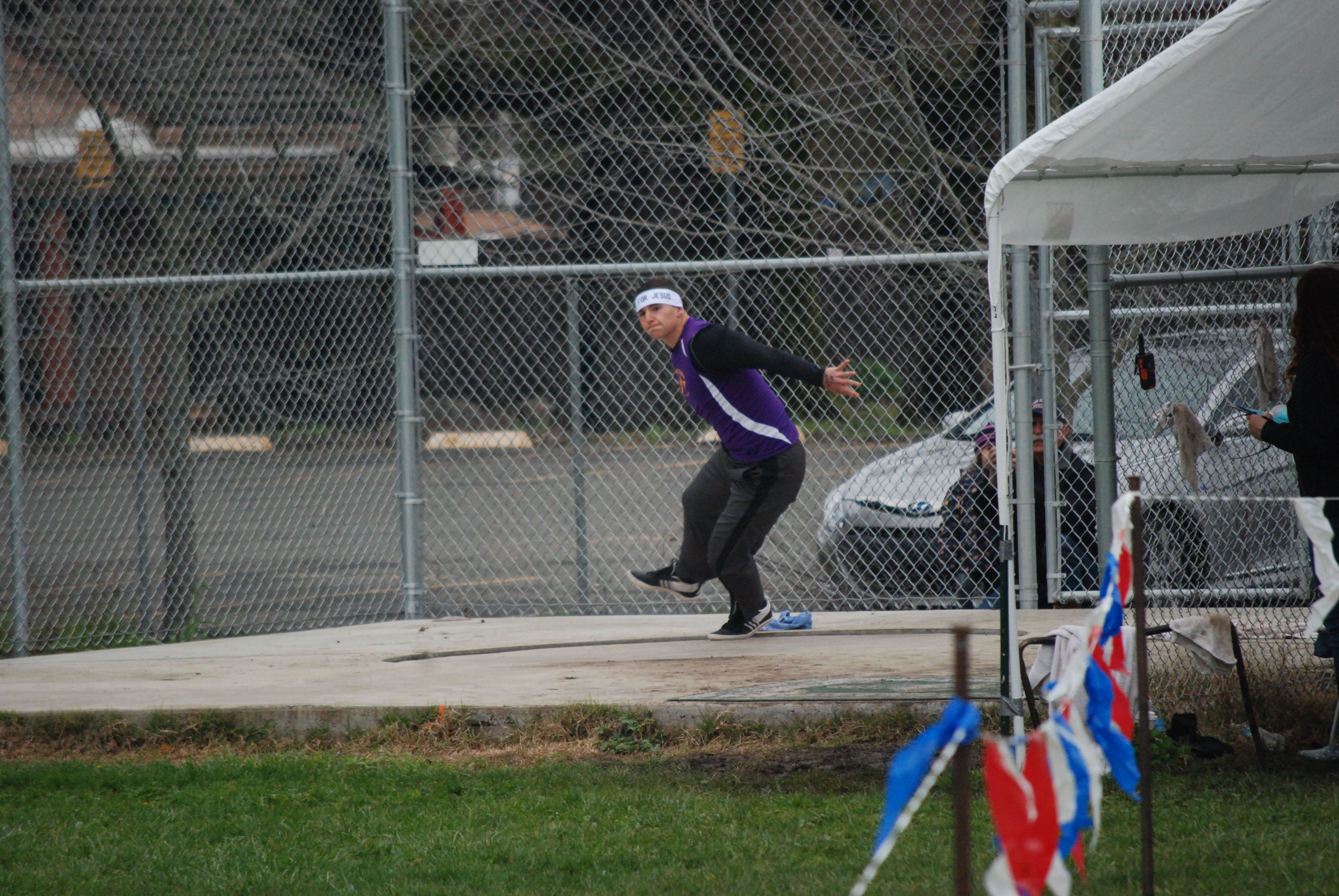 Athlete prepares for pole vault on a track with others watching.