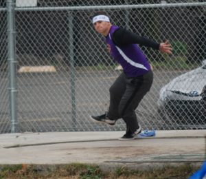 Athlete prepares for pole vault on a track with others watching.