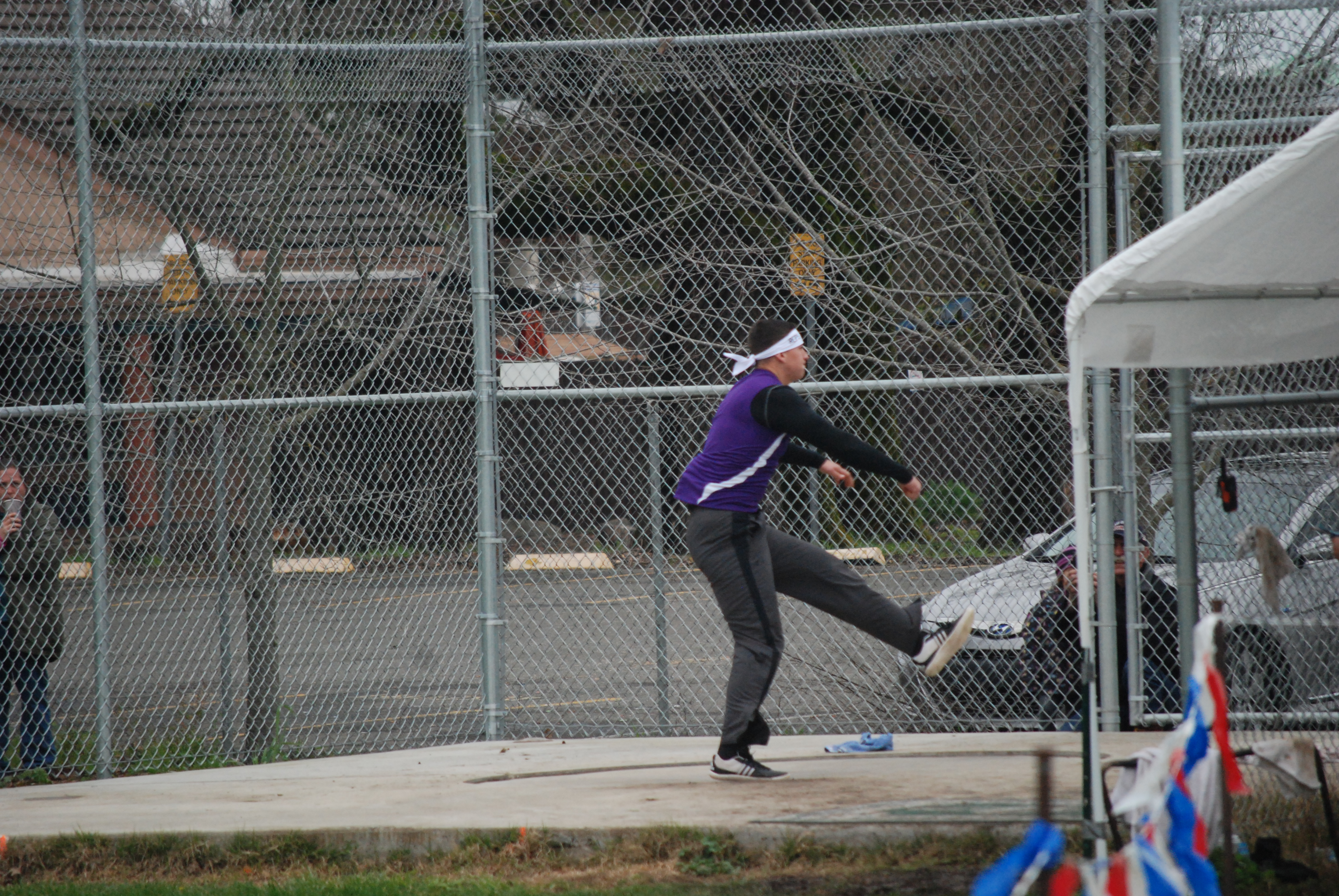 Athlete prepares for pole vault on a track with others watching.