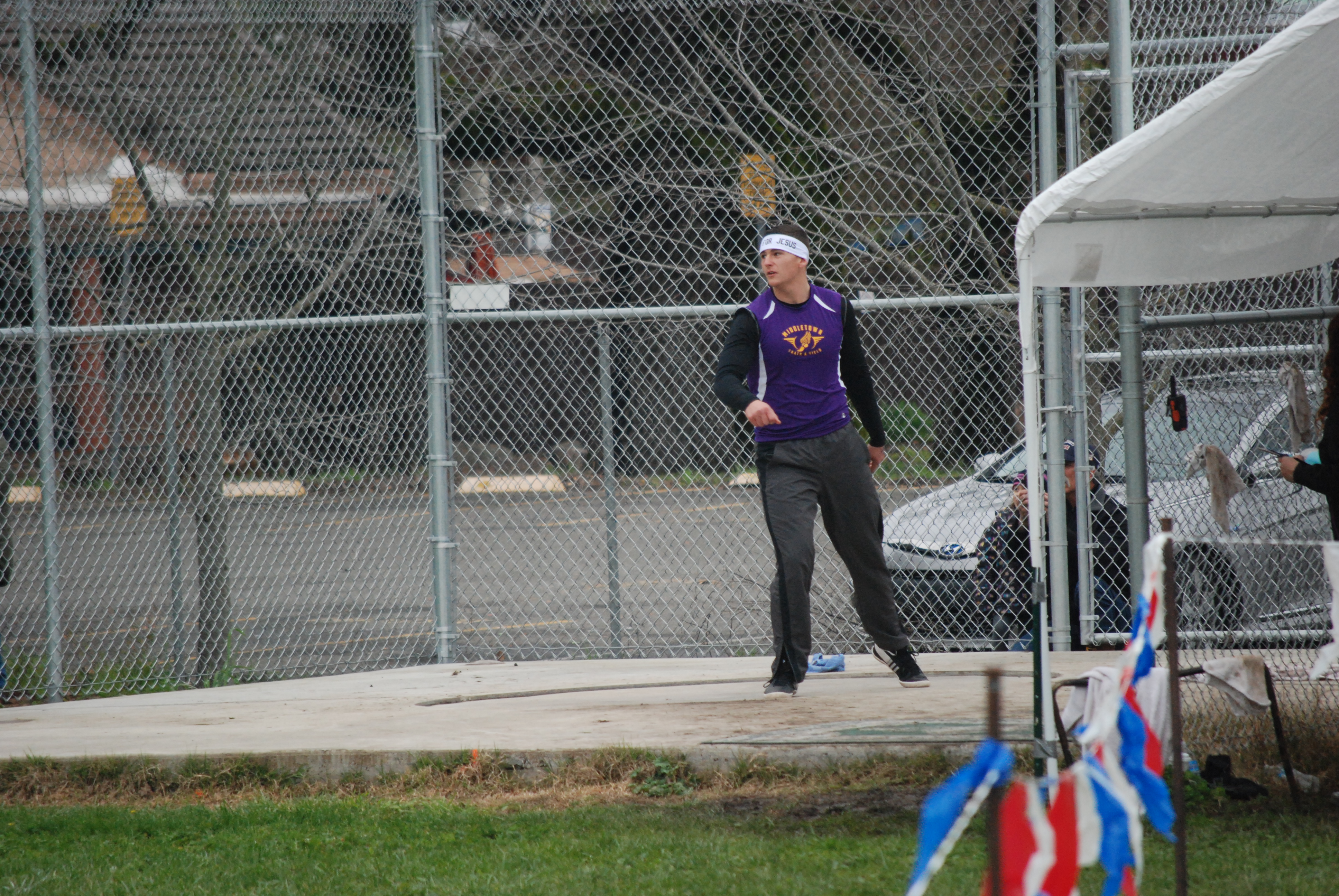 Athlete prepares for pole vault on a track with others watching.
