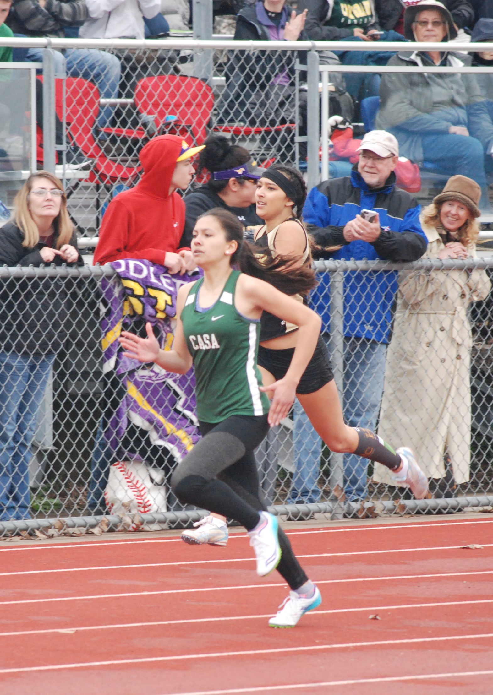 Athlete prepares for pole vault on a track with others watching.