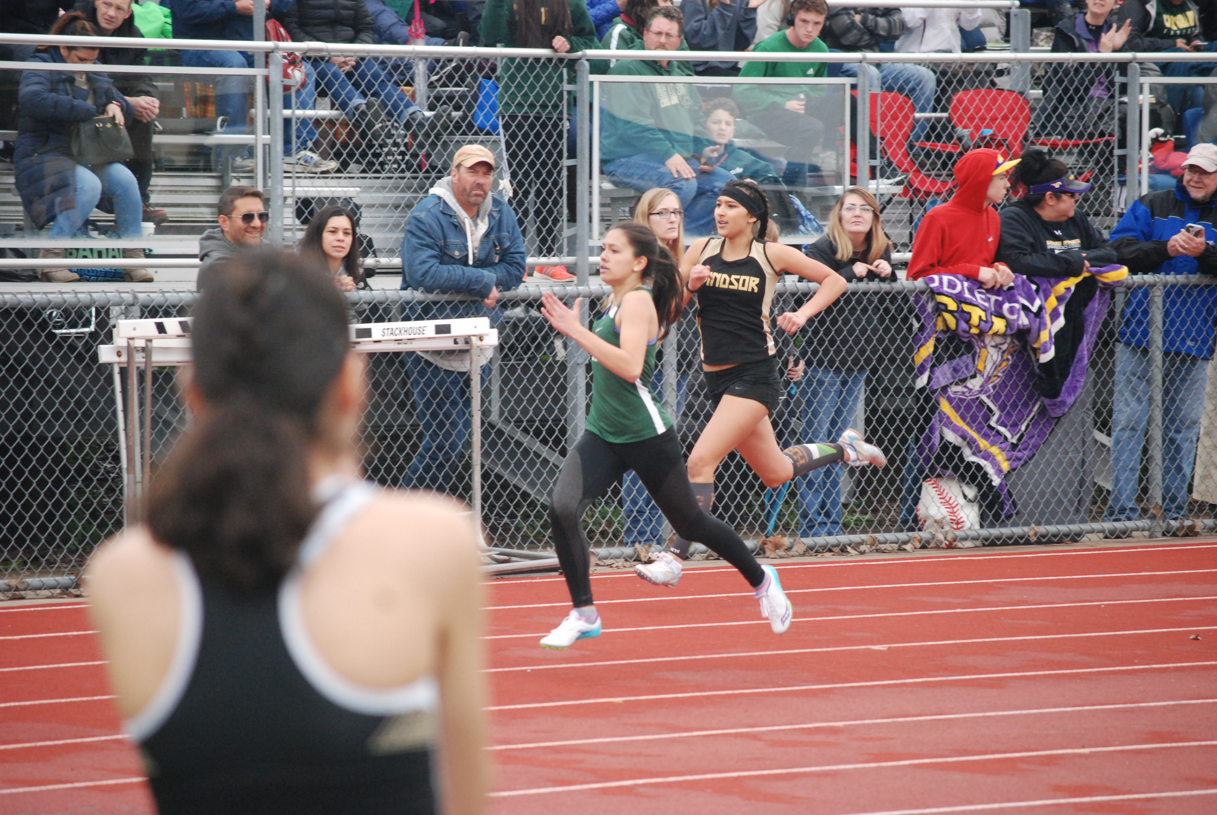Athlete prepares for pole vault on a track with others watching.