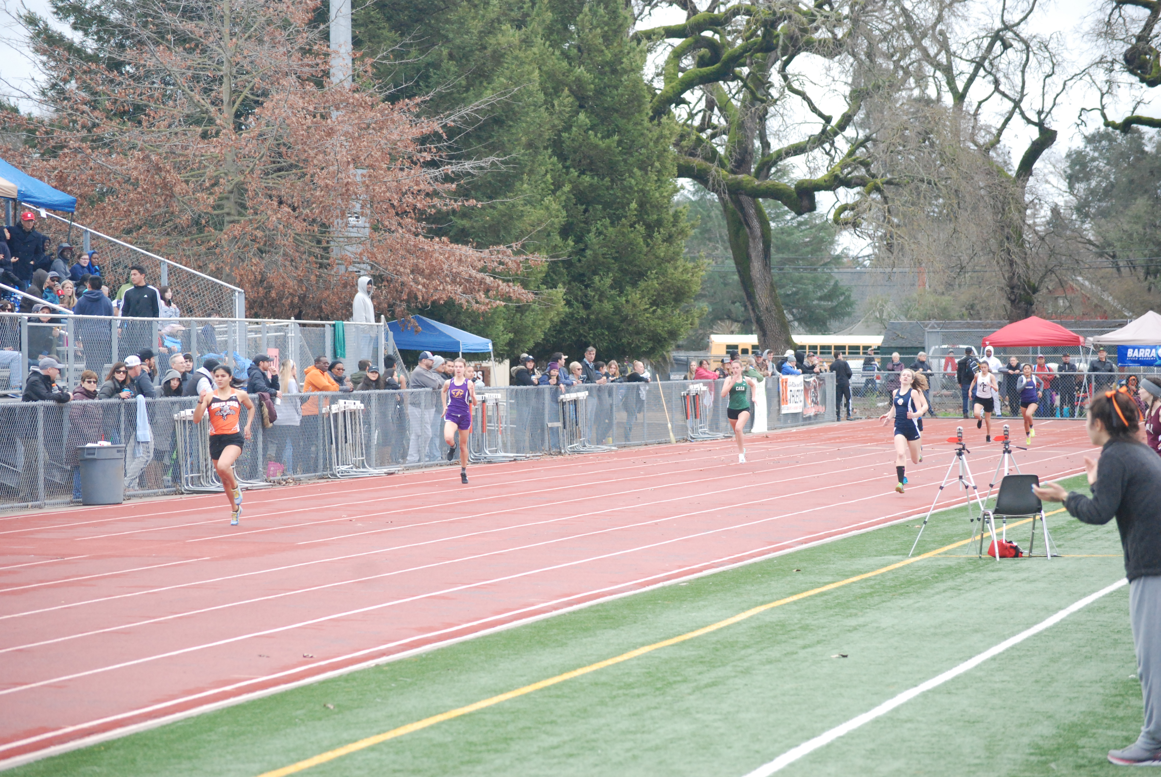 Athlete prepares for pole vault on a track with others watching.