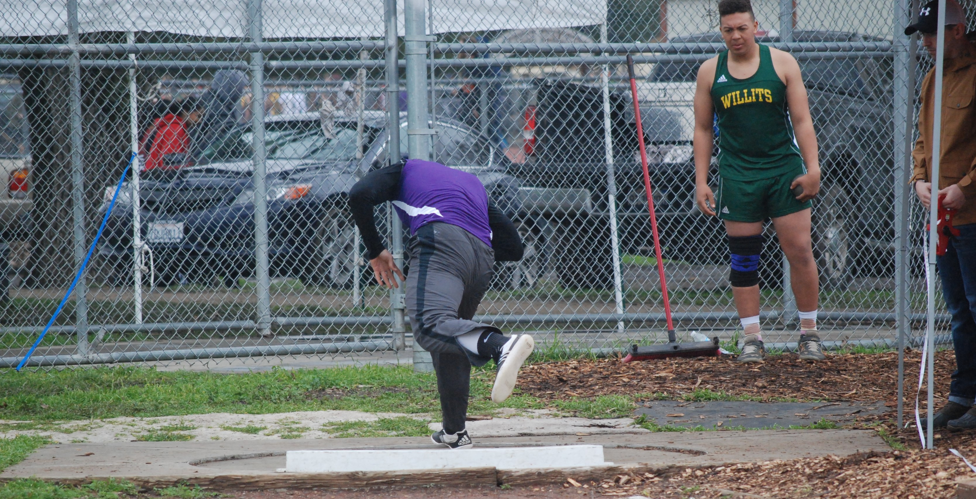 Athlete prepares for pole vault on a track with others watching.