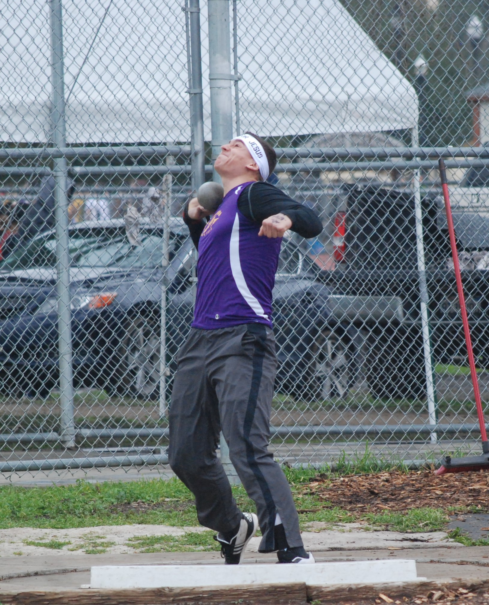 Athlete prepares for pole vault on a track with others watching.