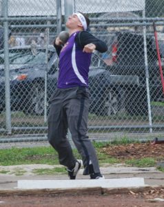 Athlete prepares for pole vault on a track with others watching.