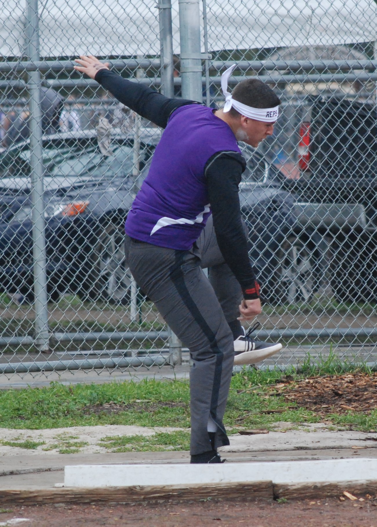 Athlete prepares for pole vault on a track with others watching.