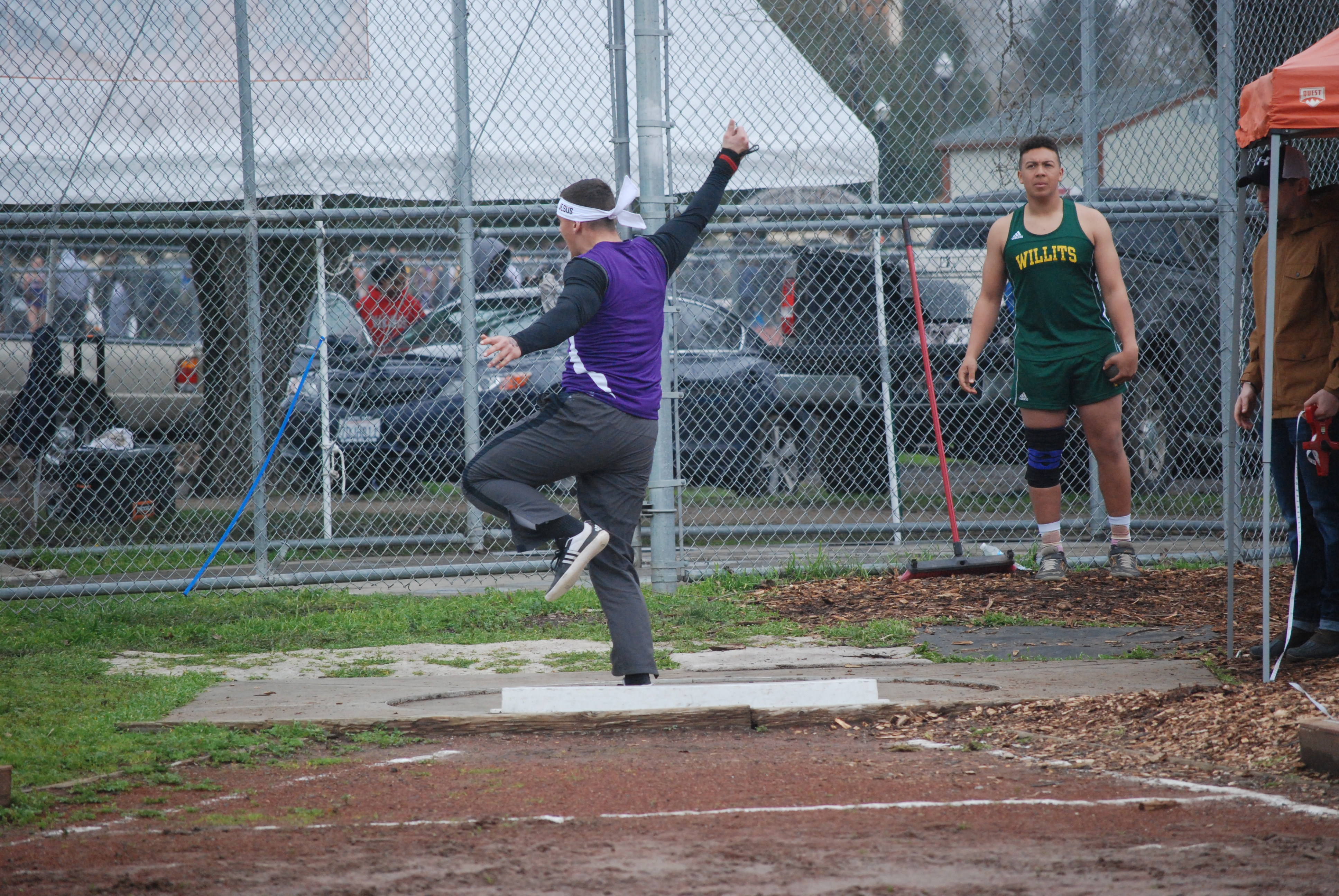 Athlete prepares for pole vault on a track with others watching.