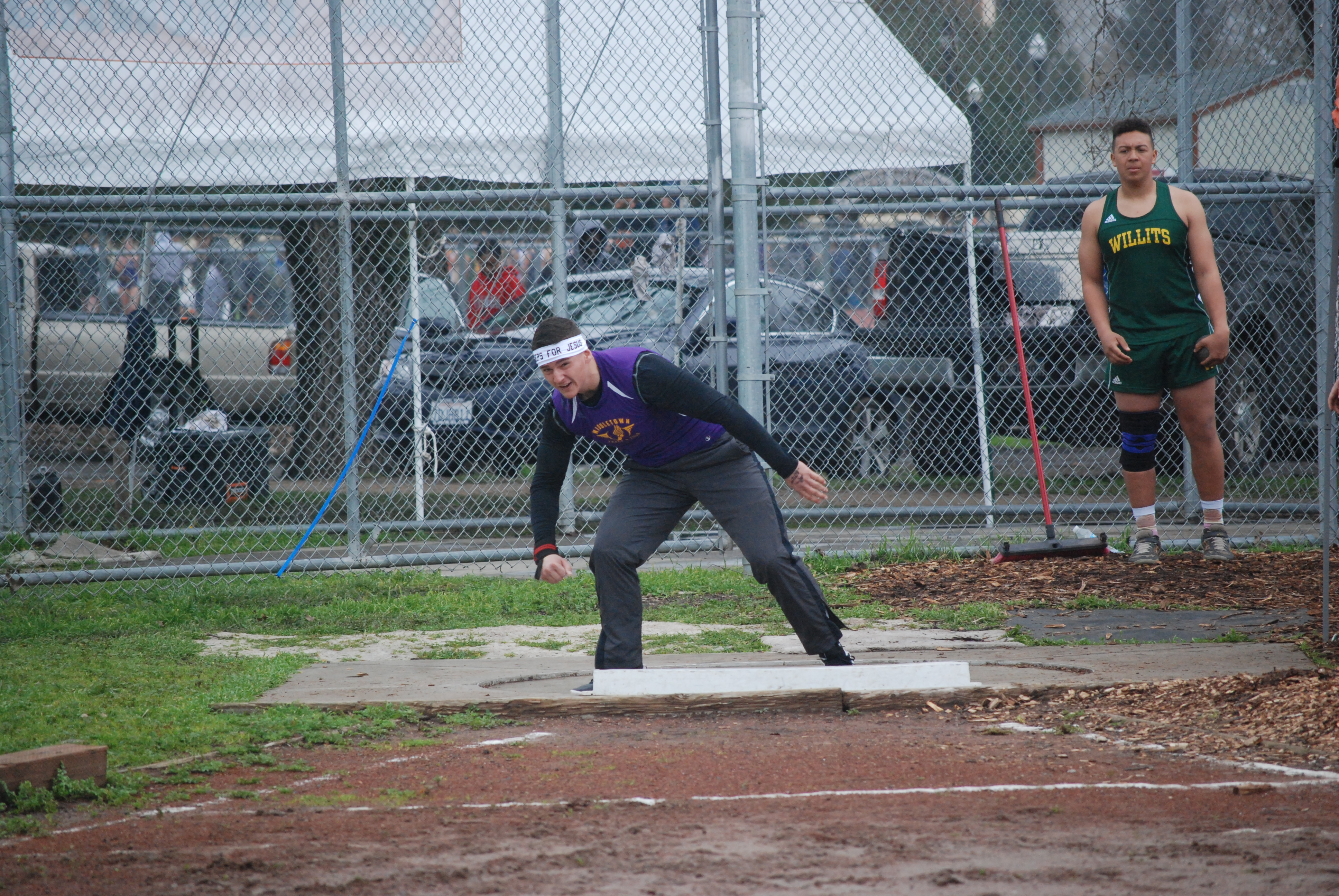 Athlete prepares for pole vault on a track with others watching.
