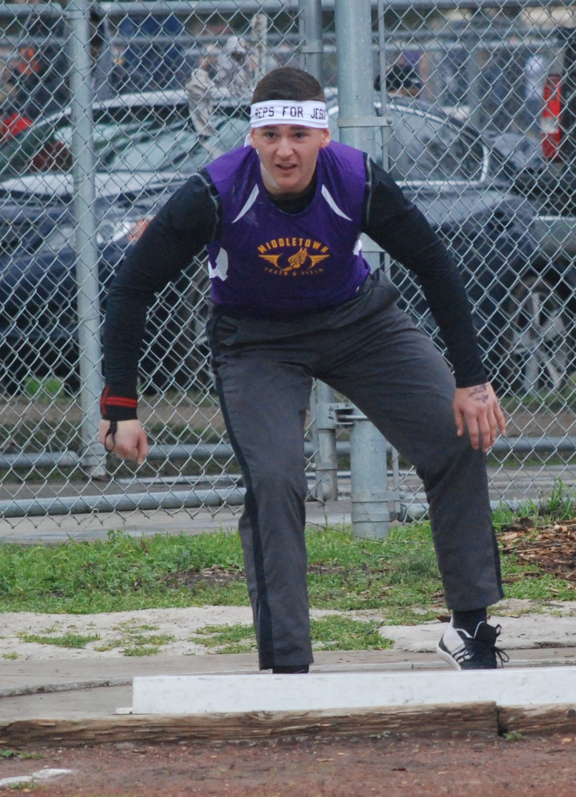 Athlete prepares for pole vault on a track with others watching.