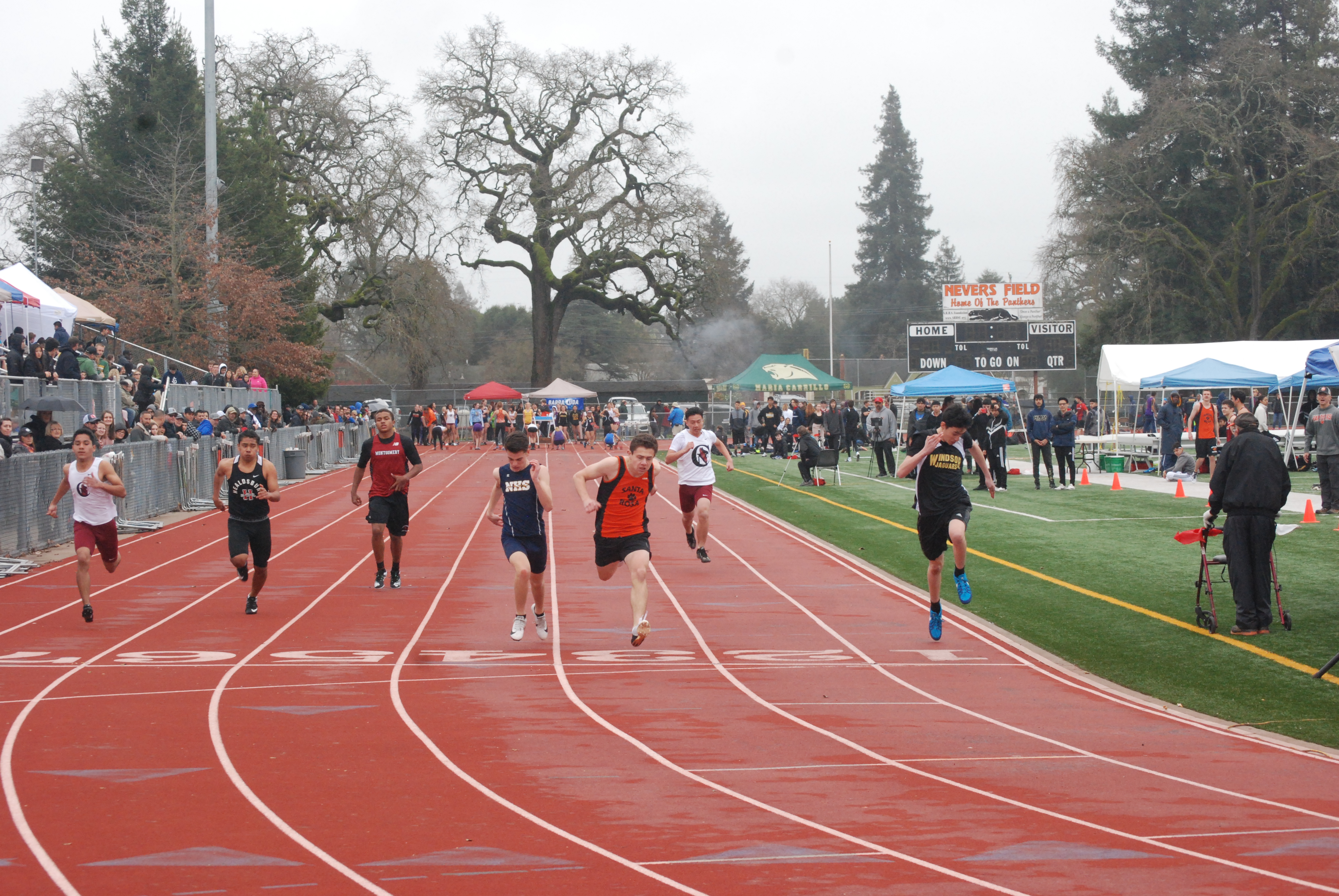 Athlete prepares for pole vault on a track with others watching.