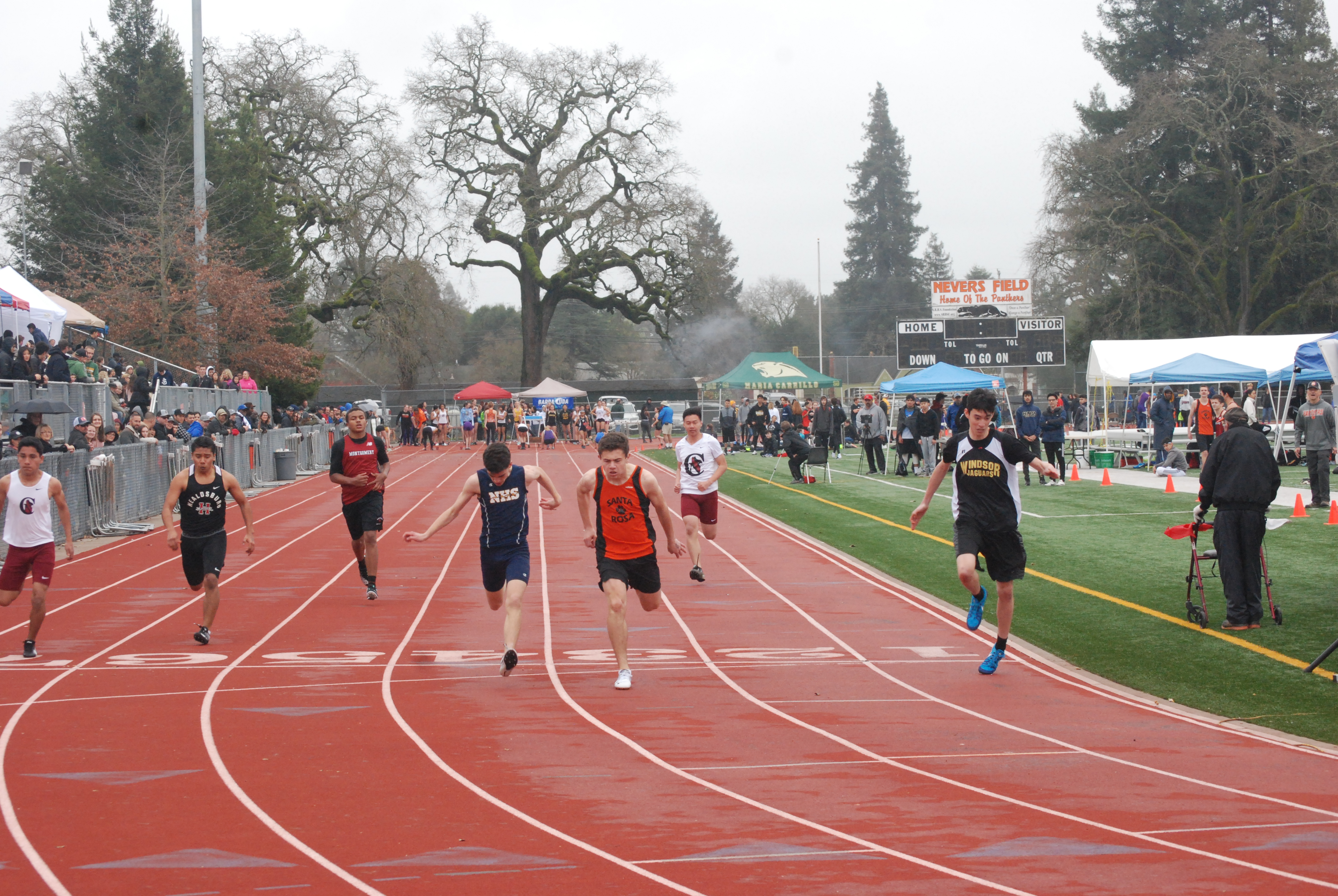 Athlete prepares for pole vault on a track with others watching.
