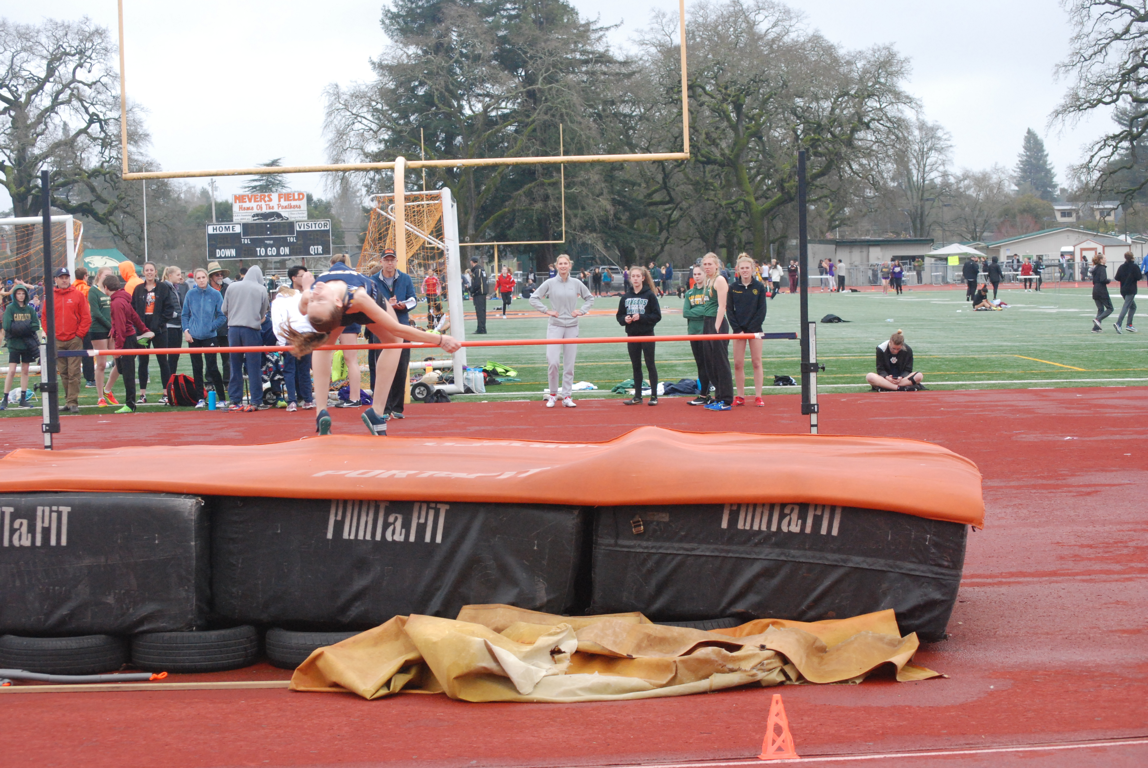 Athlete prepares for pole vault on a track with others watching.