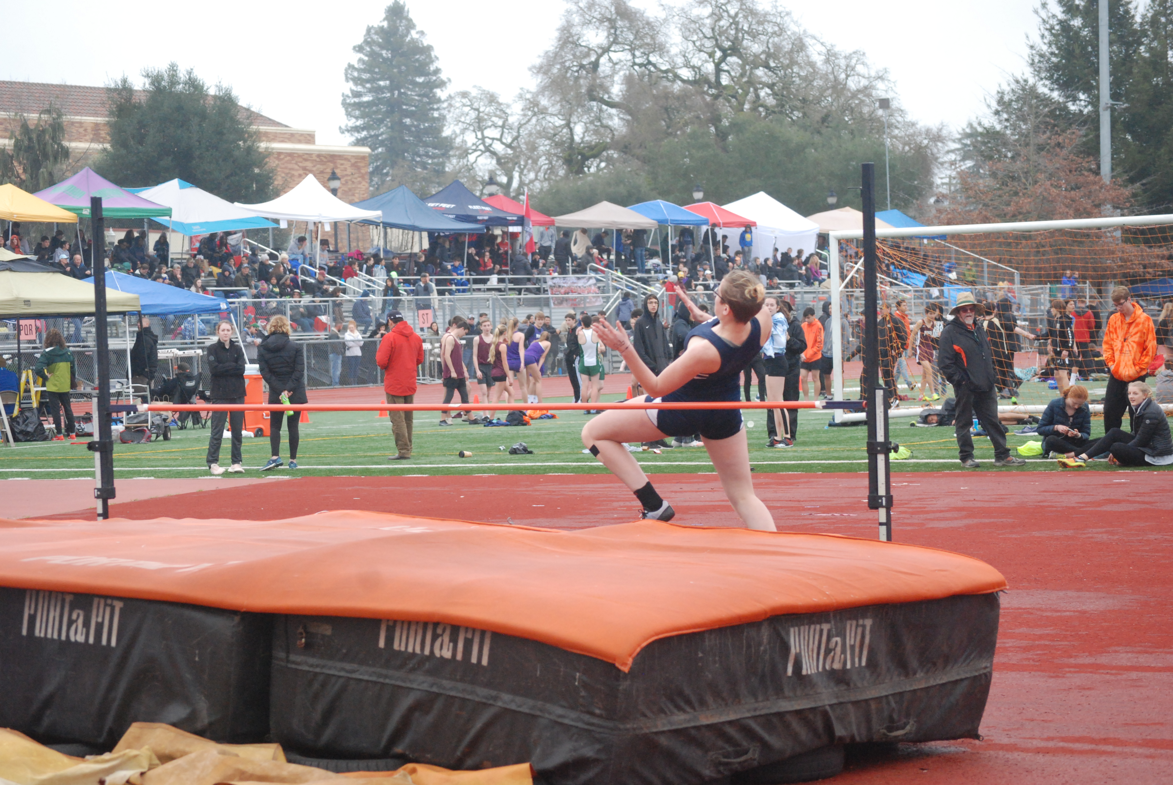 Athlete prepares for pole vault on a track with others watching.