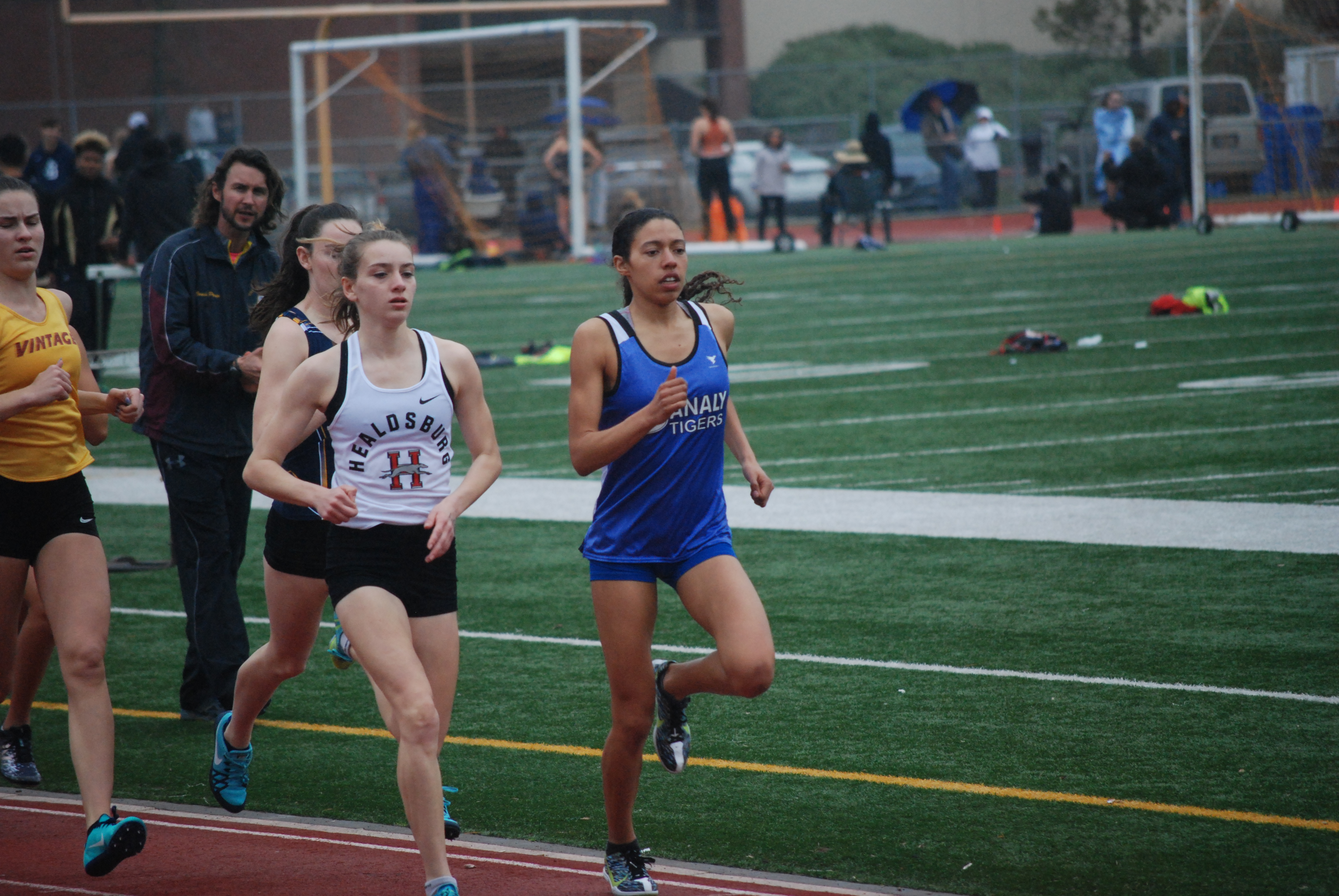 Athlete prepares for pole vault on a track with others watching.