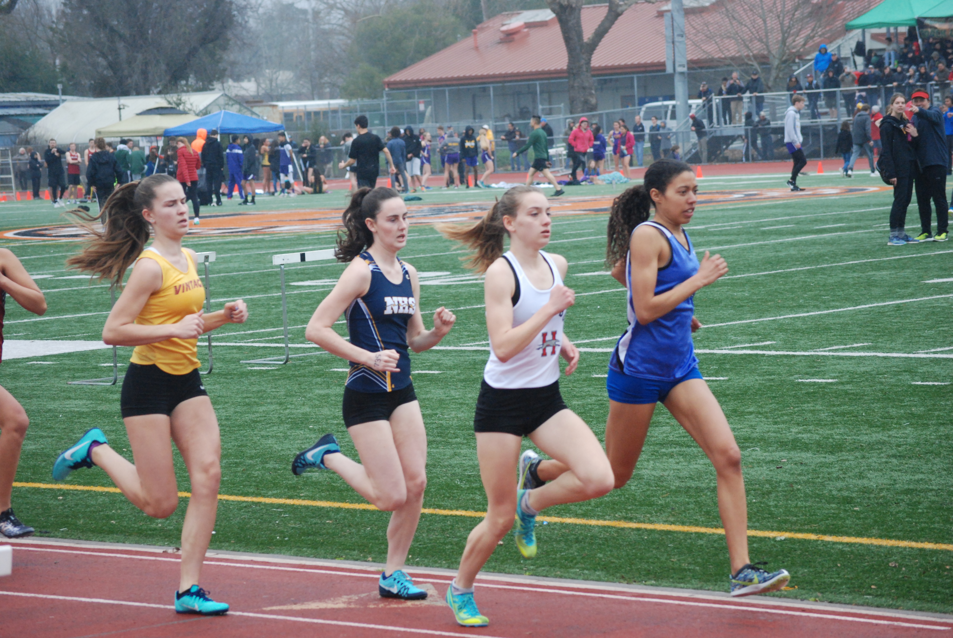 Athlete prepares for pole vault on a track with others watching.