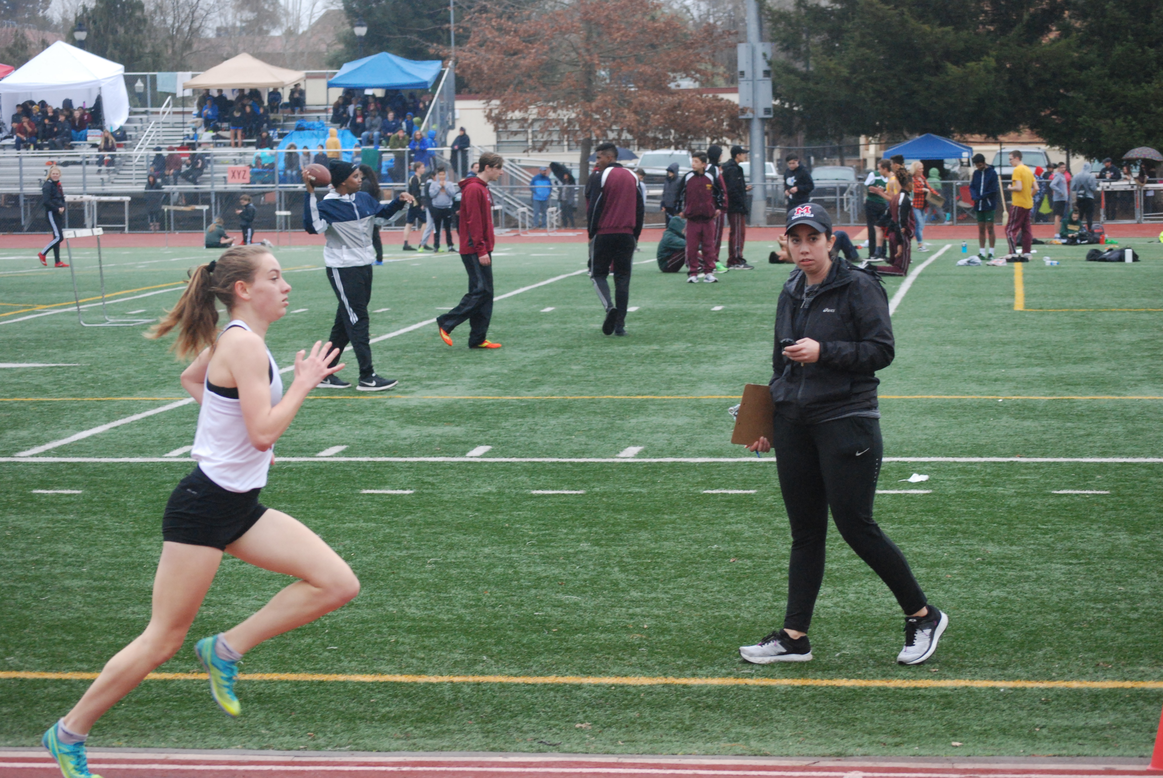 Athlete prepares for pole vault on a track with others watching.