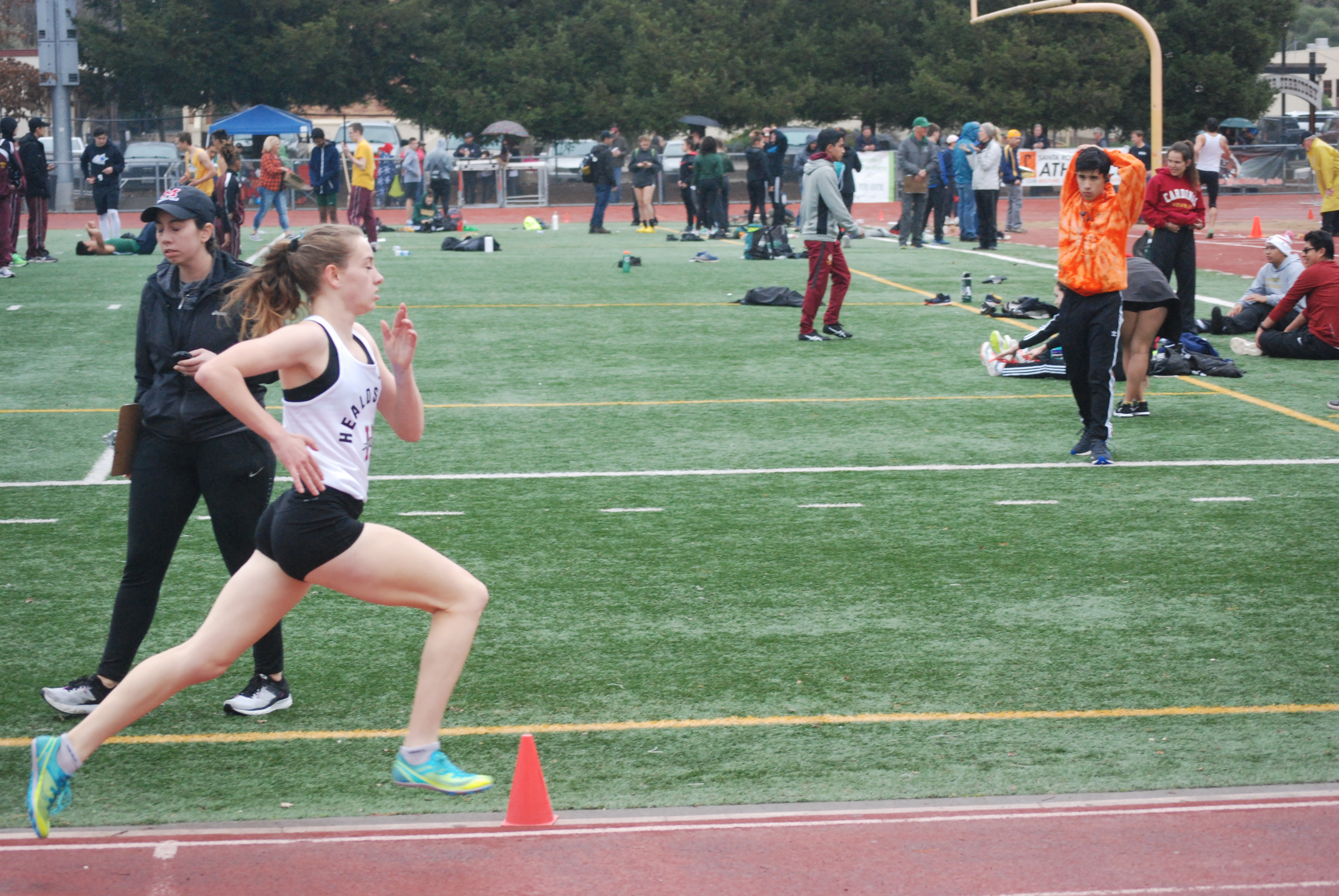 Athlete prepares for pole vault on a track with others watching.