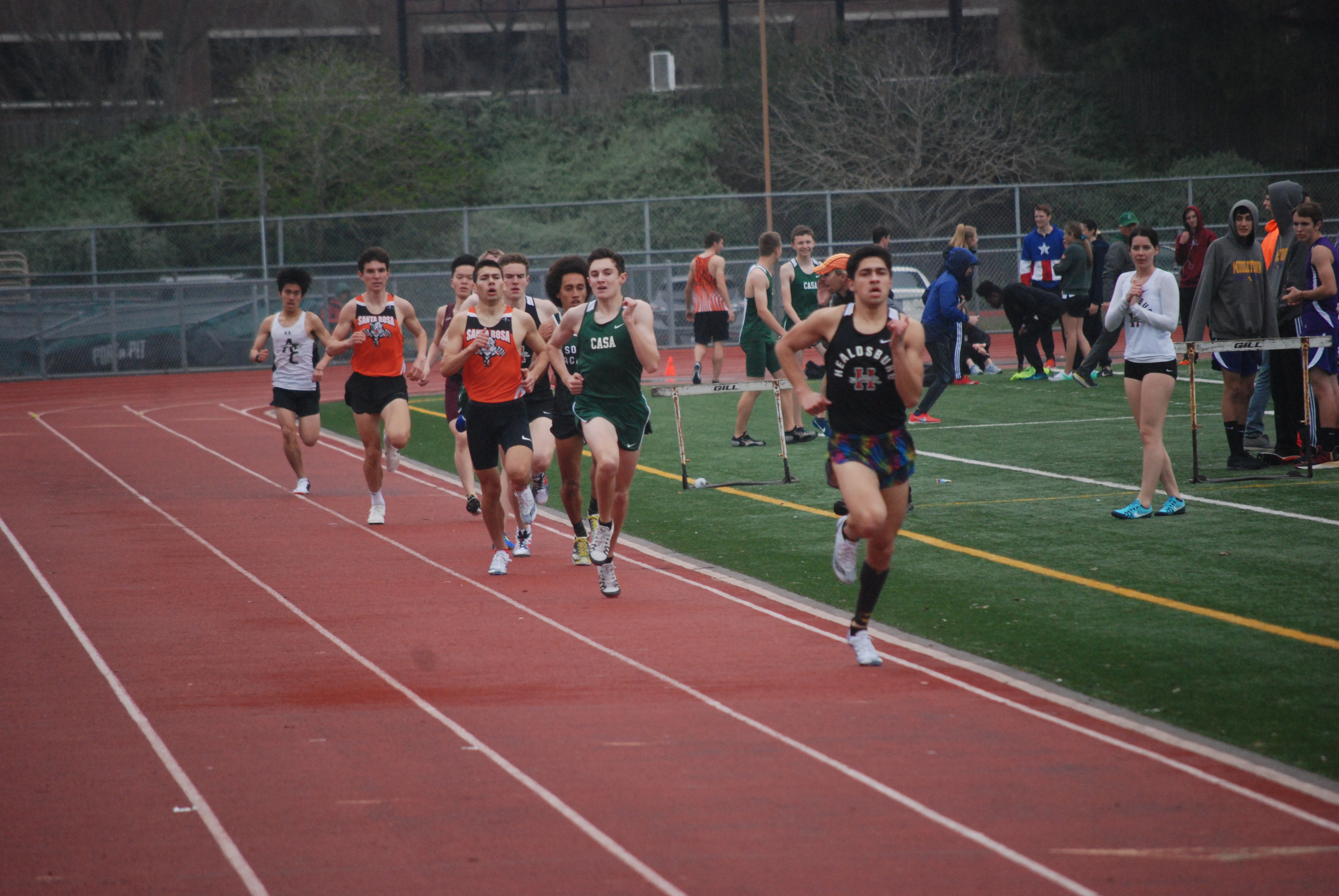 Athlete prepares for pole vault on a track with others watching.