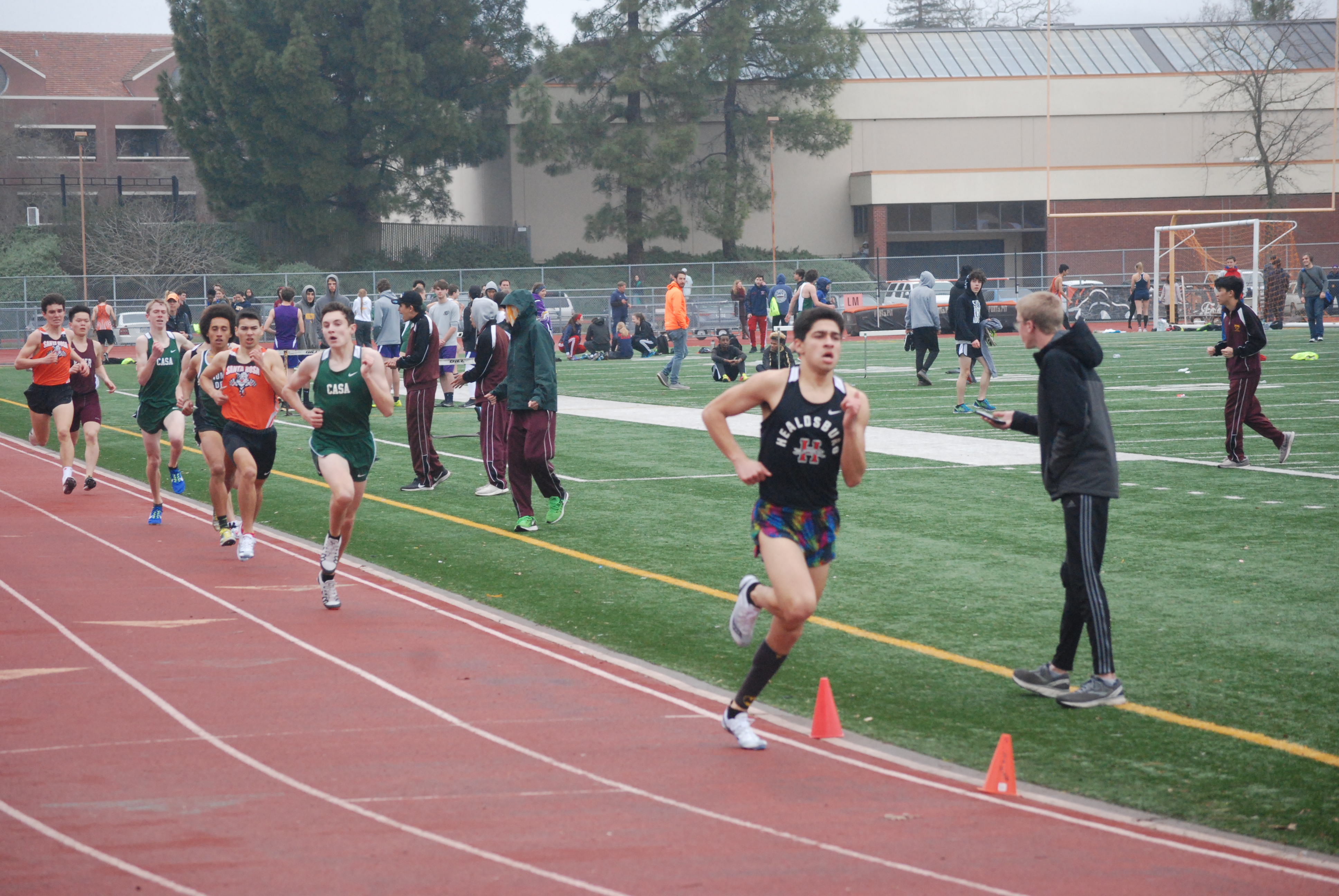 Athlete prepares for pole vault on a track with others watching.