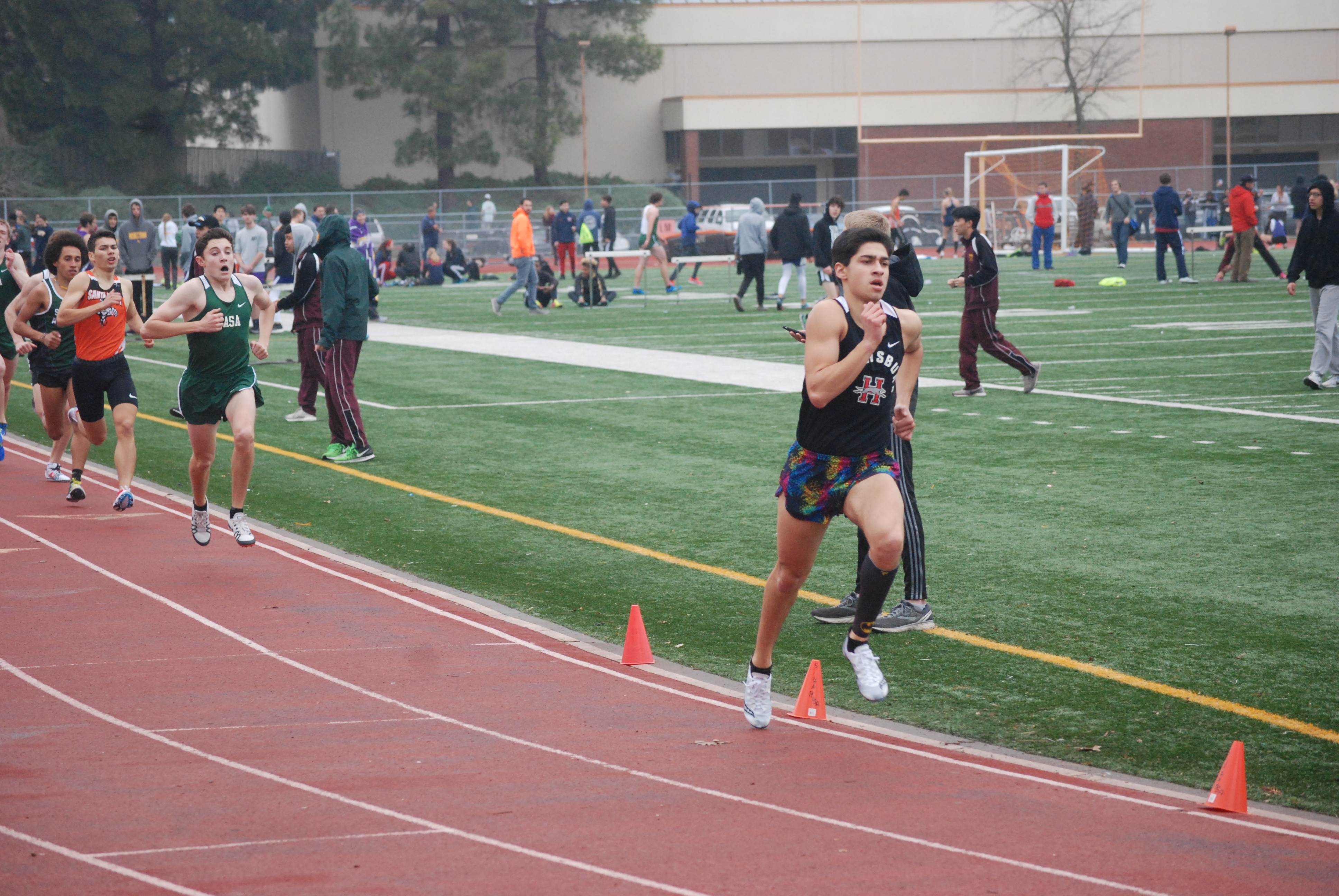Athlete prepares for pole vault on a track with others watching.