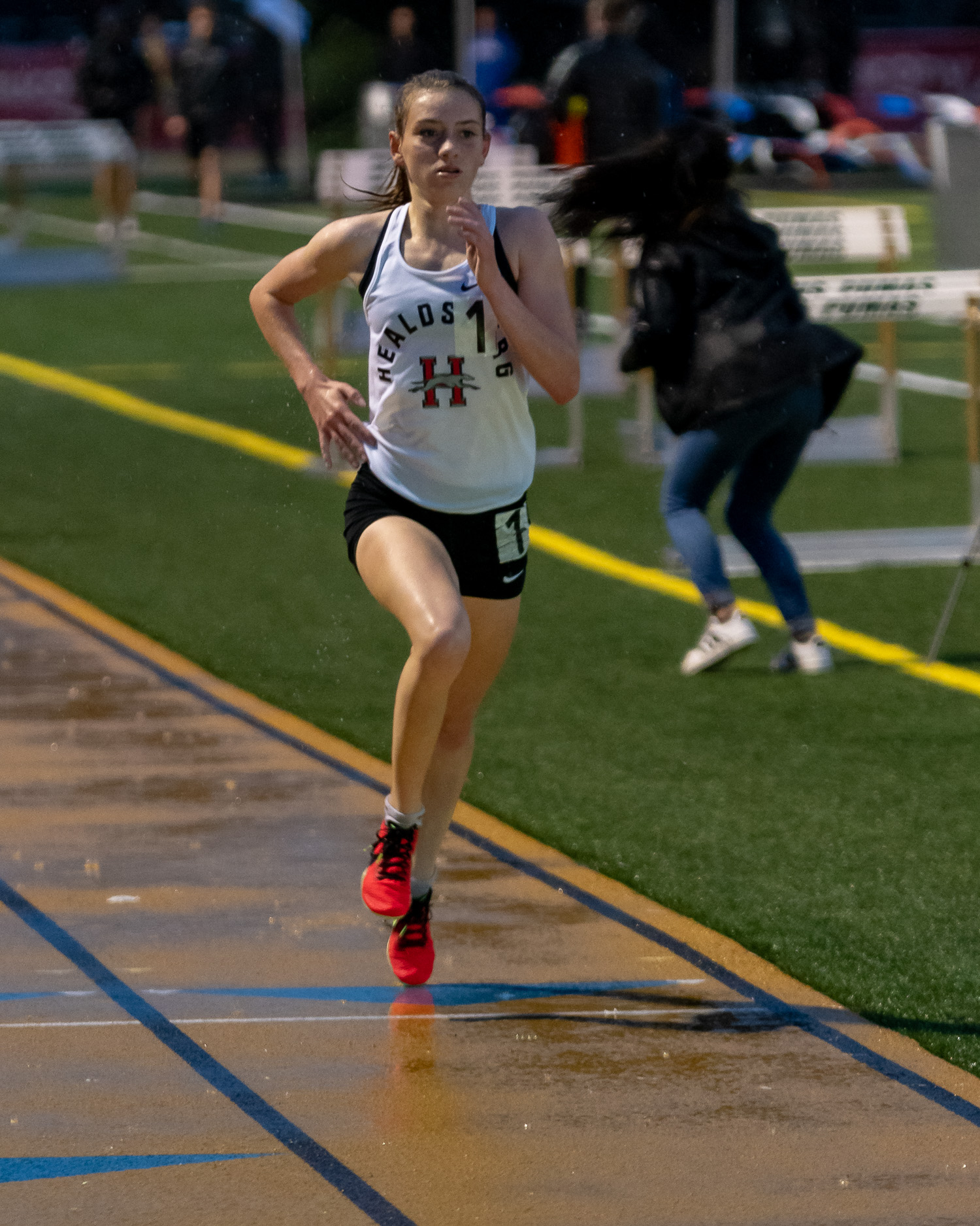 Athlete prepares for pole vault on a track with others watching.